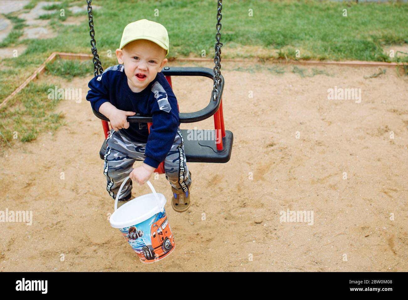 Der Junge ist grimacing, auf einer Schaukel reiten Stockfoto