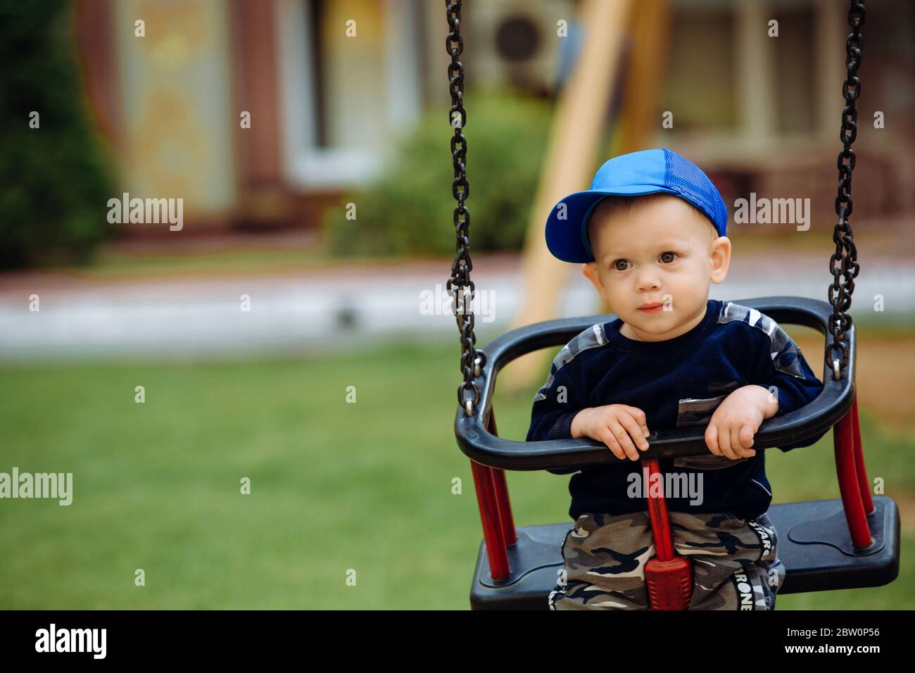 Schöner Junge 1-2 Jahre alt, auf einer Schaukel, Spielplatz, Nahaufnahme Stockfoto