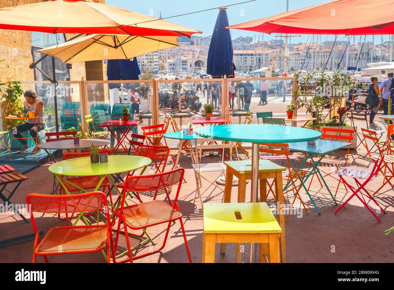 Sommer Straßencafé mit bunten Tischen und Stühlen und Blick auf Böschung und Kai in Marseille, Frankreich, Provence Stockfoto