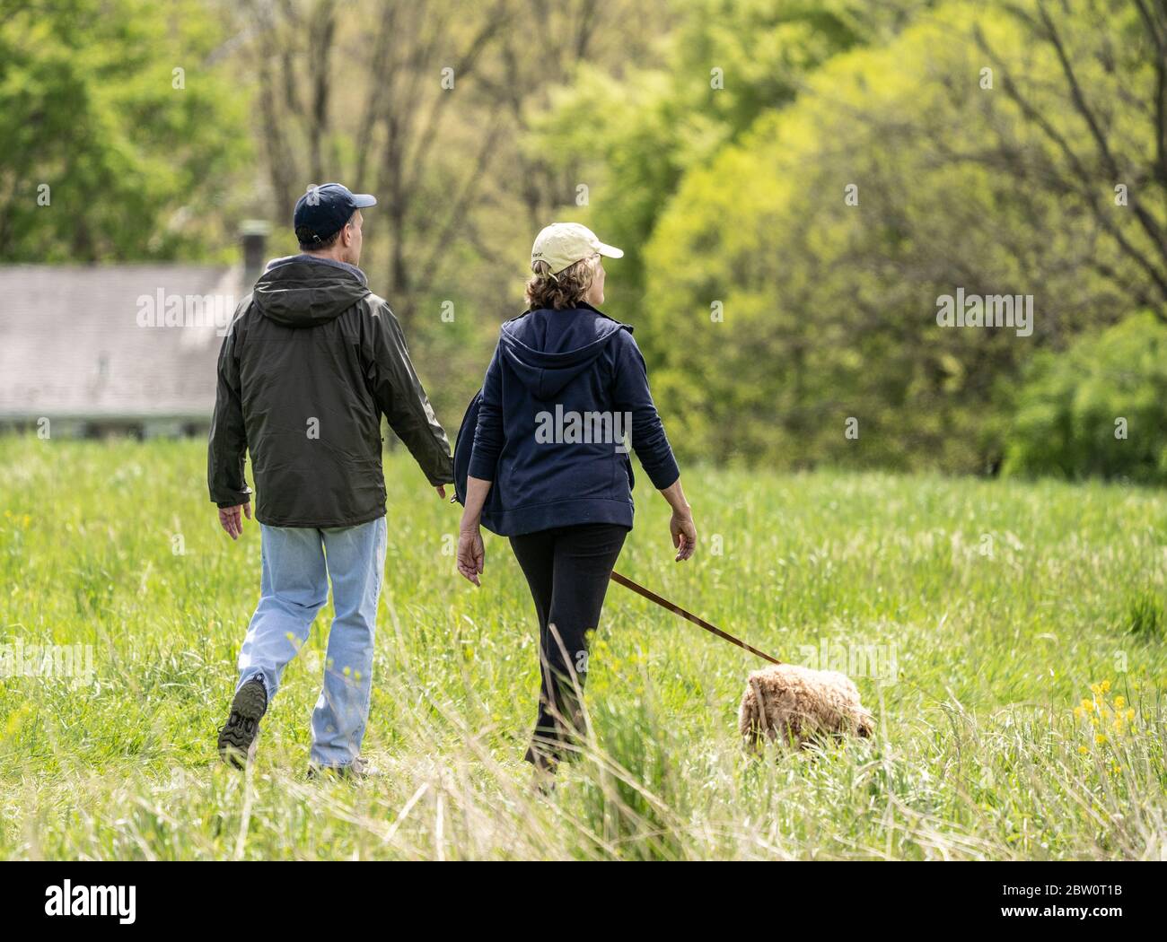 Berks County, Pennsylvania - 5. Mai 2020: Ältere Paar nimmt Hund für einen Spaziergang im Park am Frühlingsnachmittag. Stockfoto