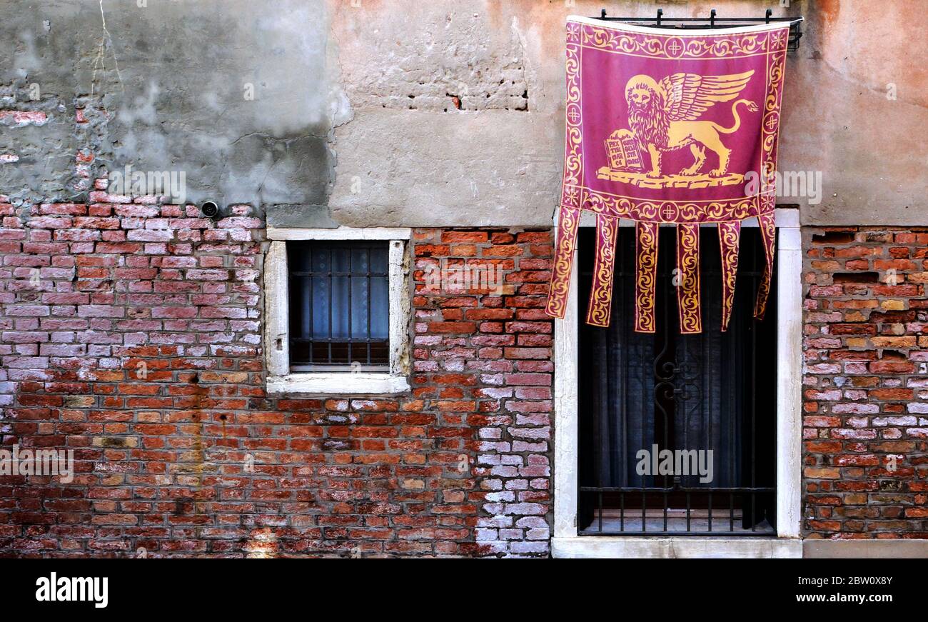 Die venezianische Flagge mit dem symbolischen 'geflügelten Löwen', bekannt als das Banner des Hl. Markus, ist stolz ausgestellt. Stockfoto