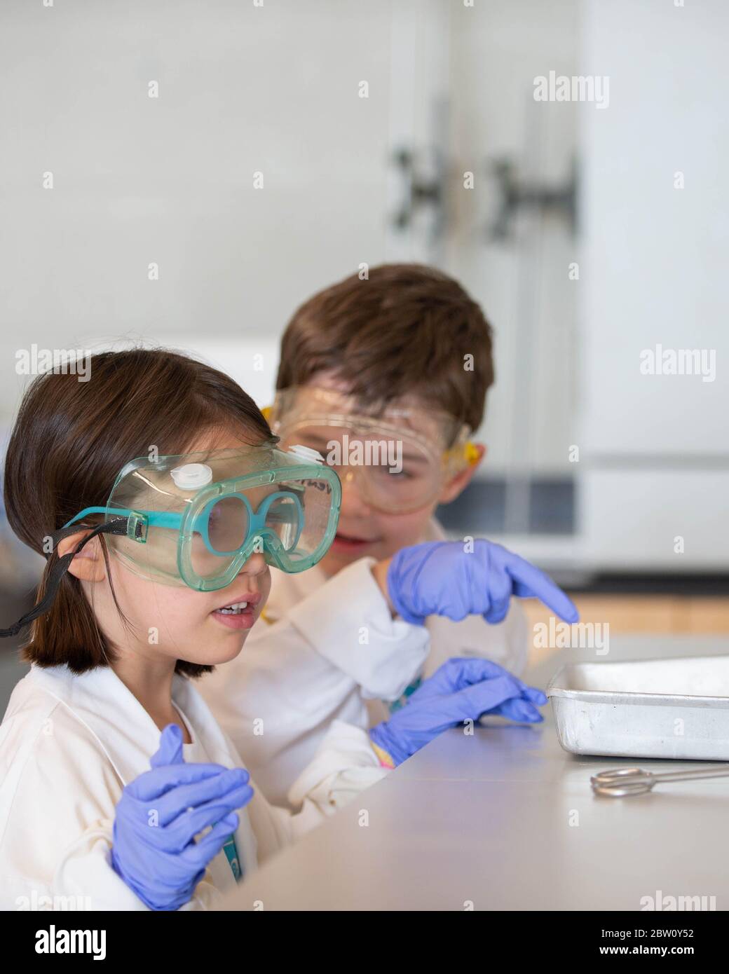 Junge Studenten, die ein wissenschaftliches Experiment in einem Chemielabor durchführen! Sie haben ihre Laborkittel und Schutzbrille an, Sicherheit geht vor! Stockfoto