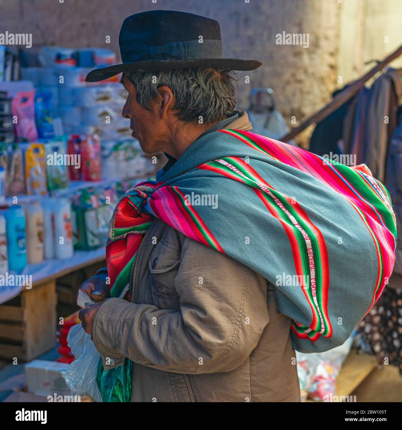 Porträt eines indigenen bolivianischen Tarabuco-Mannes mit seinem bunten Stoff, der als Tasche auf dem lokalen Markt in der Nähe von Sucre City, Bolivien verwendet wird. Stockfoto
