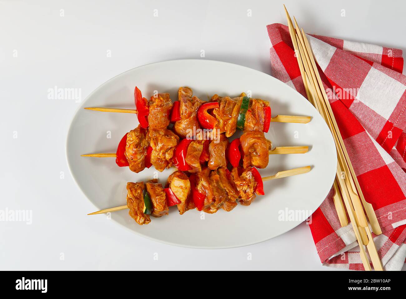 Rohes mariniertes Hühnerfleisch auf Holzspießen, Schwein, Huhn, Rindfleisch in weißem Teller auf weißem Hintergrund. Stockfoto