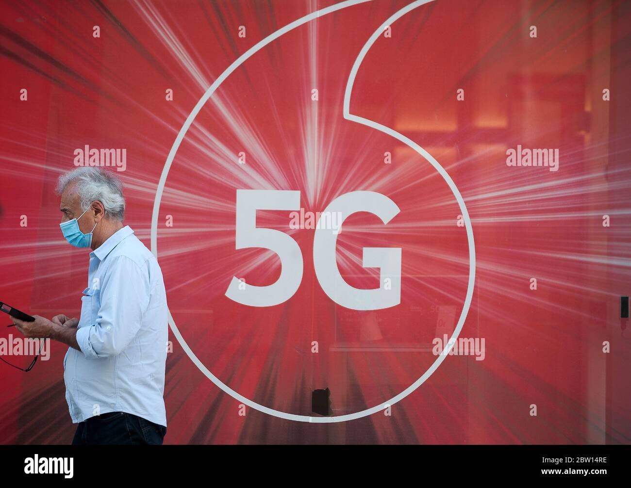 Malaga, Spanien. Mai 2020. Ein Mann, der vorbeugend eine Gesichtsmaske trägt, überprüft sein Mobiltelefon, während er in der Phase 1 an 5G-Werbung vorbeigeht, während die teilweise Sperrung im Land fortgesetzt wird.Spanien durchläuft einen Plan, um durch Lockerung der Maßnahmen, die sich aus der ergeben, auf eine "neue Normalität" hinzuarbeiten COVID-19 Ausbruch. Quelle: SOPA Images Limited/Alamy Live News Stockfoto