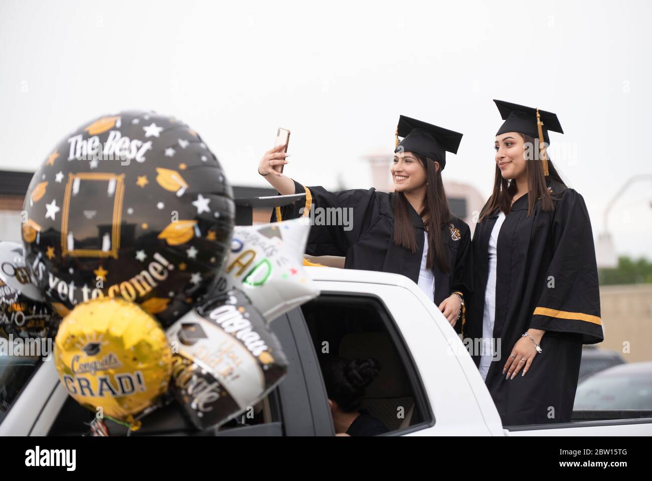 Absolventen der Navarro Early College High School, darunter Esmerelda Alvarez (l.) und Alma Pina, marschieren am 28. Mai 2020 durch ihre Nachbarschaft in Nord-Austin, um ein akademisches Finale zu feiern, das durch die Coronavirus-Pandemie verkürzt wurde. Etwa 200 Absolventen stapelten sich in Autos und winkten Familie und Freunden in der zwei-Meilen-Parade zu. Kredit: Bob Daemmrich/Alamy Live News Stockfoto