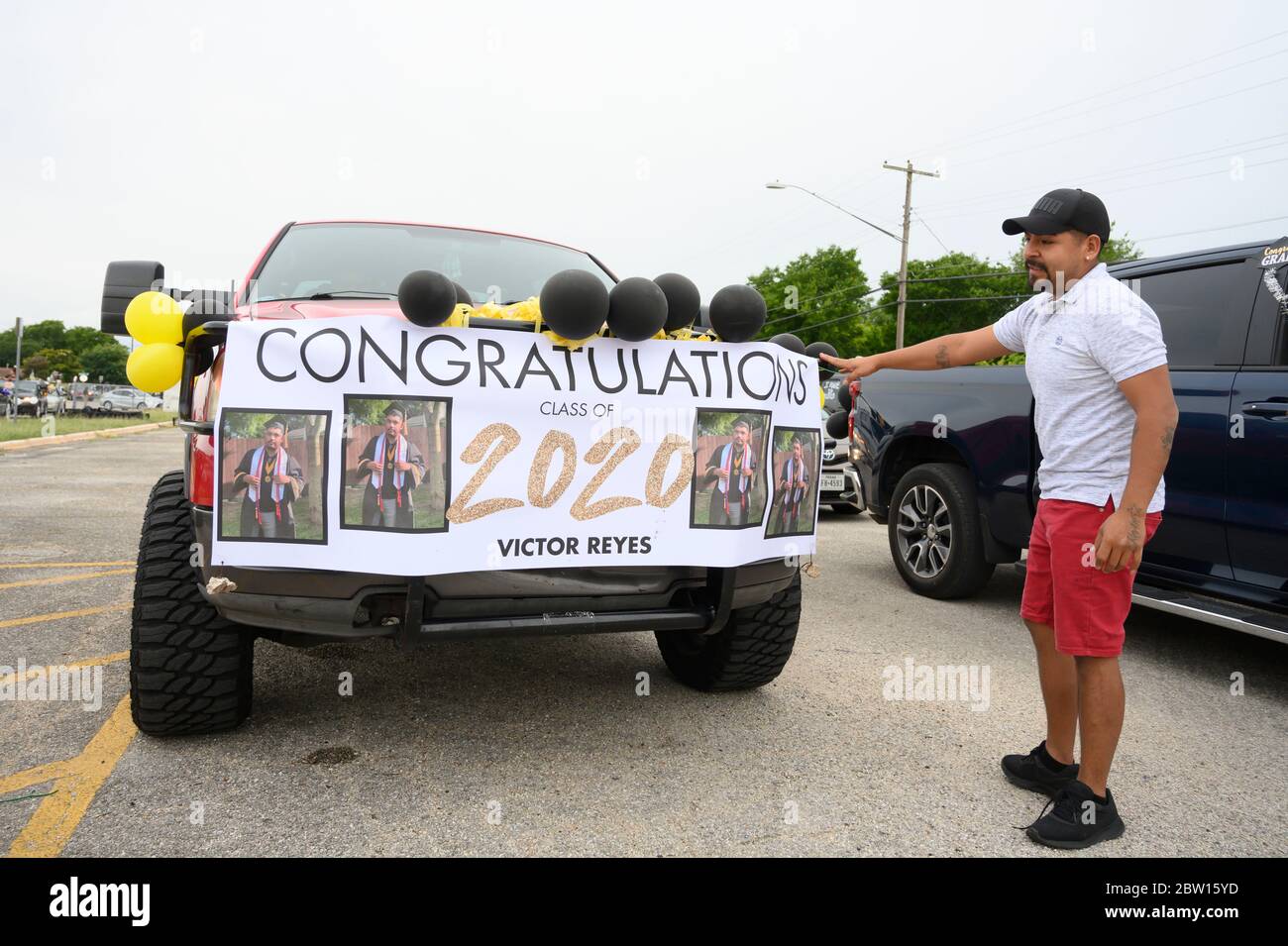 Luis Reyes, Vater von Victor Reyes, zeigt auf das Banner seines Sohnes, als die Absolventen der Navarro Early College High School sich darauf vorbereiten, durch ihre Nachbarschaft im Norden von Austin, Texas, zu marschieren, um ein akademisches Finale zu feiern, das durch die Coronavirus-Pandemie verkürzt wurde. Stockfoto