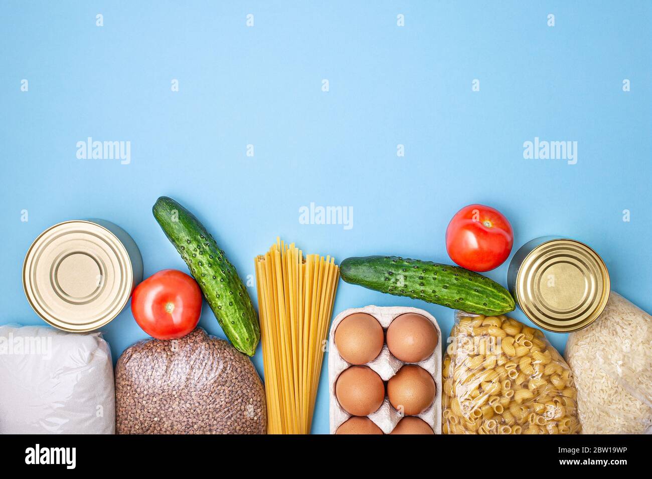 Lieferkost. Reis, Buchweizen, Nudeln, Dosenfutter, Zucker auf blauem Hintergrund. Sammeln Sie freiwillig Lebensmittel. Spende, Quarantäne des Coronavirus. Speisenangebot Stockfoto