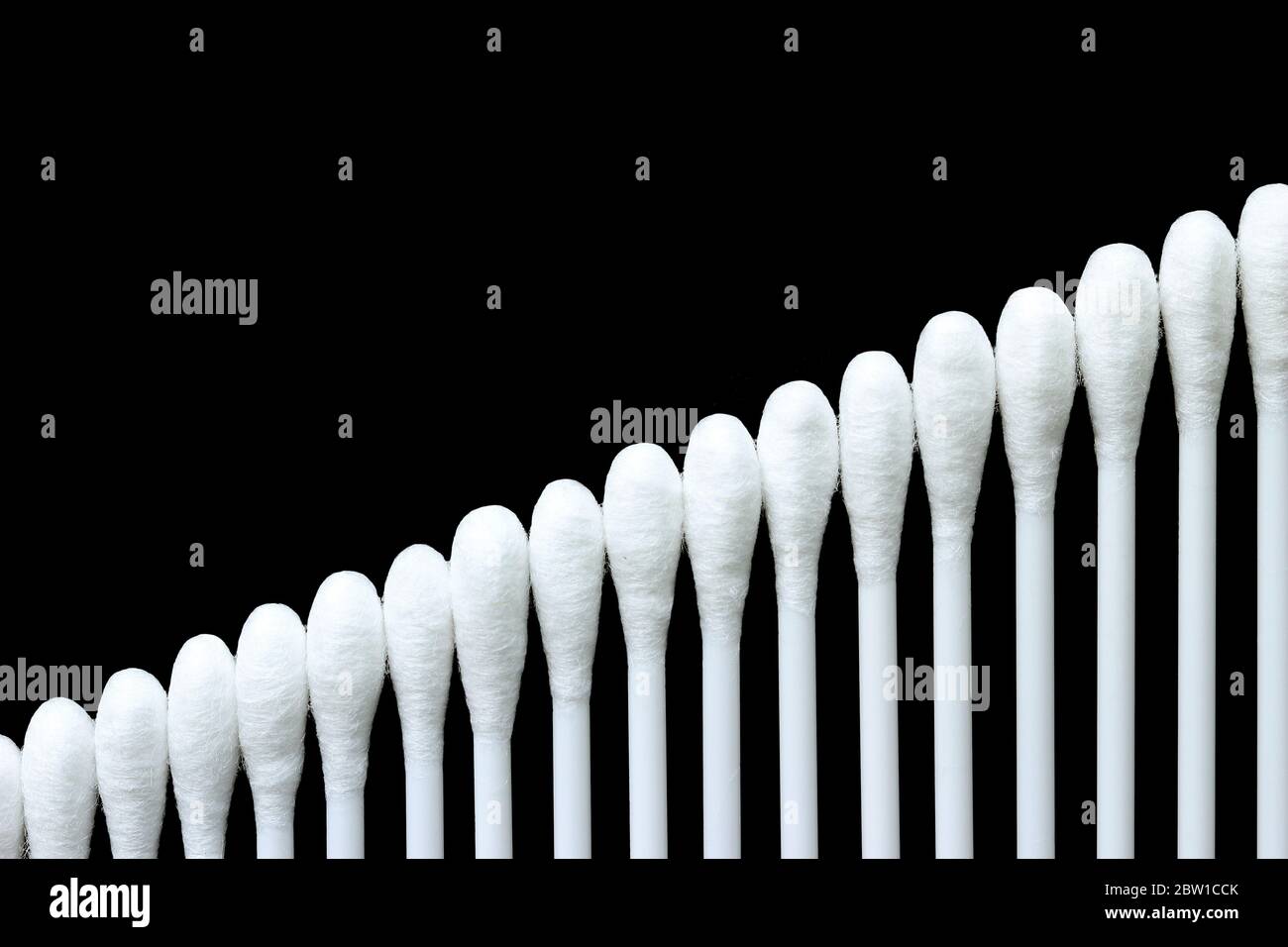 Weiße Wattestäbchen sind auf eine geordnete und schöne Weise auf schwarzem Hintergrund angeordnet. Stockfoto