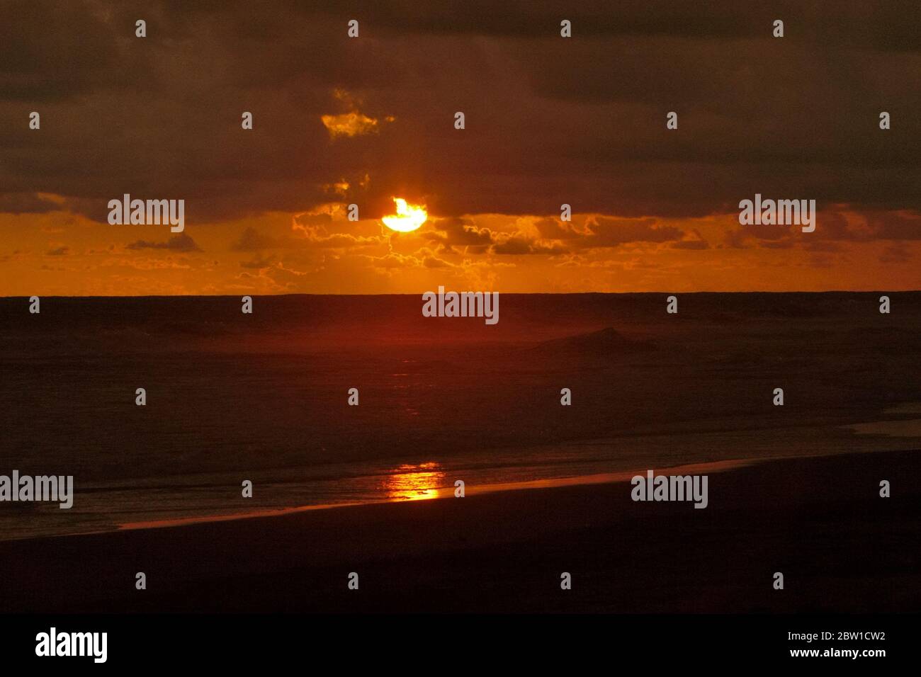 Blick auf Regenwolken über dem Indischen Ozean mit Meereswellen, die sich dem flachen Wasser nähern, von der Westküste Sumatras kurz vor Sonnenuntergang gesehen. Stockfoto