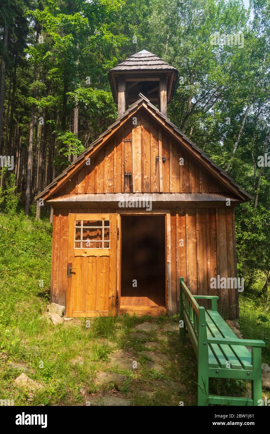 Kleine Holzkapelle mit Bank und Wald im Hintergrund über Vrbno pod Pradedem Stadt in Jeseniky Berge in Tschechien Stockfoto