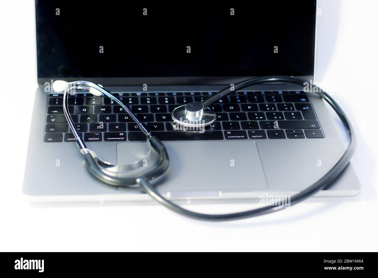 Nahaufnahme eines Laptops mit einem Stethoskop auf weißem Hintergrund, Computervirus-Konzept Stockfoto