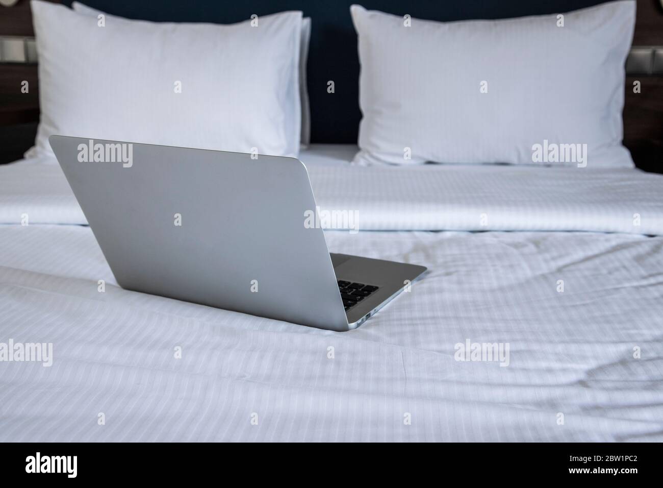 Laptop auf weißem Bett Work-at-Home-Konzept Stockfoto