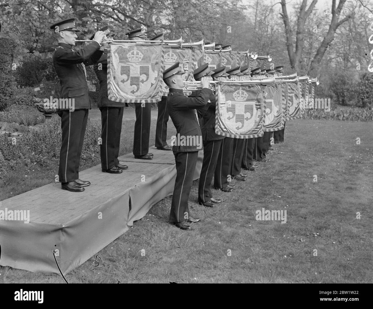 Krönungsfanfare. Trompeter üben in der Kneller Hall. Mit ihren Trompeten, die mit bunten Bannern aufgehängt sind, 50 Trompeter der Royal Military School of Music Practice in Kneller Hall, Twickenham, die Fanfaren, die sie bei der Krönung in Westminster Abbey erklang. Foto zeigt: Ein Trompeter, der in der Kneller Hall die Krönungsfanfare erklingt. 19. April 1937 Stockfoto