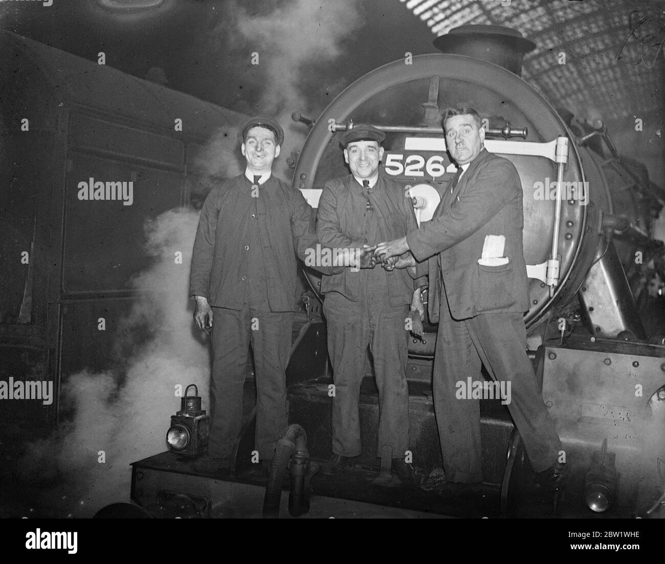 Der 'Hill Climb'-Zug setzt Rekord für Manchester und zurück. Die speziell gebaute LMS Bergsteigerlokomotive kam in St Pancras an, nachdem sie Rekorde für die London nach Manchester und zurück gelaufen hatte. Auf der Fahrt nach oben kam der Zug in Manchester drei Stunden 22 Minuten und auf der Rückfahrt die hundert und 83 Meilen in drei Stunden 27 Minuten. Auf jeder Fahrt Schnitt sie mehrere Minuten von ihrem Zeitplan ab, was eine halbe Stunde weniger war als der normalerweise laufende Zug. Foto zeigt, von links nach rechts, F Foulkes , der Feuerwehrmann GH Beebe, Fahrer und Inspector Foulkes, die sich vor dem Rekord die Hände schütteln. Stockfoto