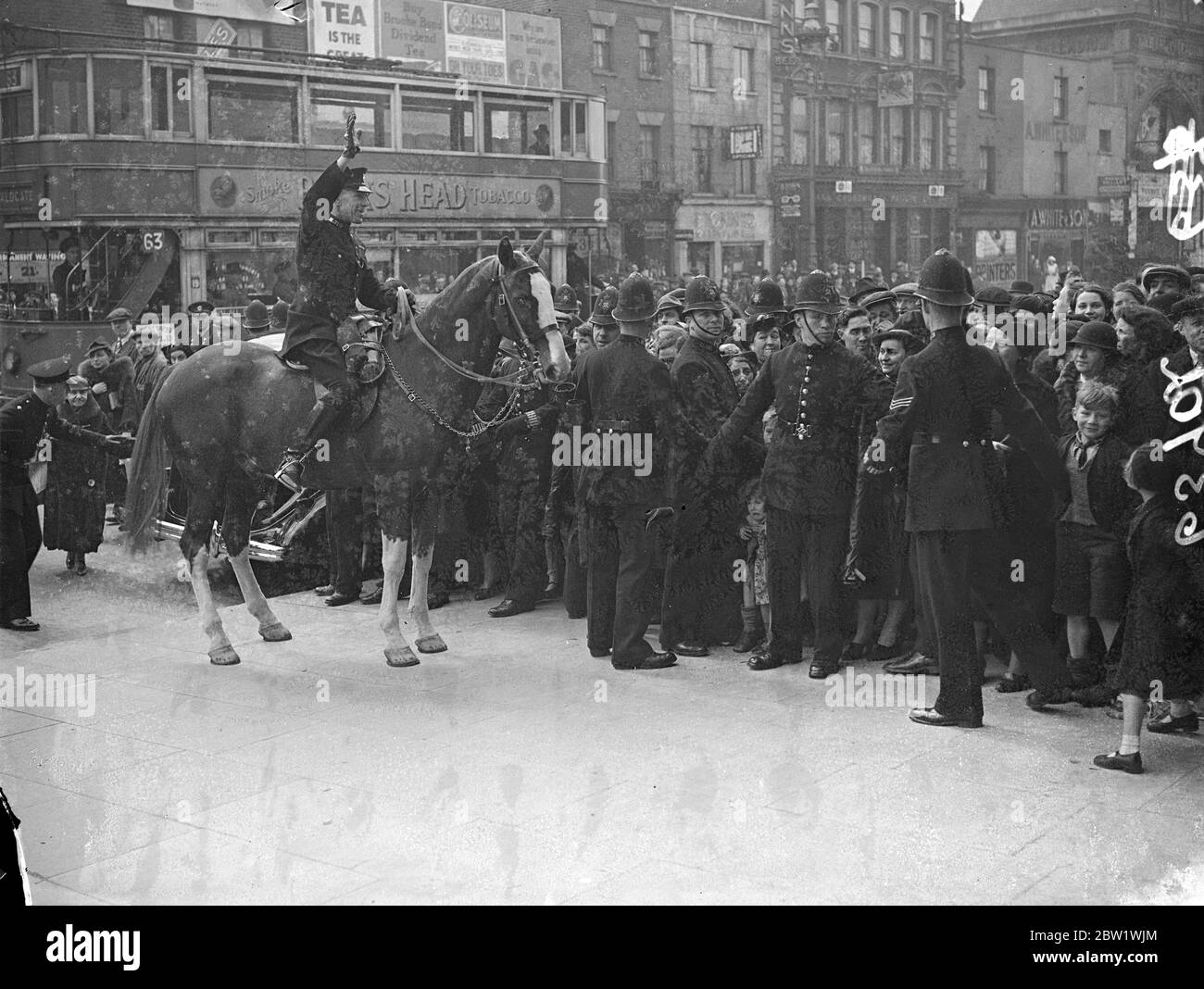 Der Herzog und die Herzogin von Kent bei Krönungskonzert im East End. Montierte Polizei kontrollieren Massen. Der Herzog und die Herzogin von Kent nahmen an einem Kinderkonzert im Volkspalast, Mile End Road, Teil. Auf dem Programm steht ein besonderes Krönungsstück von Sir Walford Davies, Meister der Königsmusik, das Prinzessin Elizabeth (heute 11 Jahre alt) und Prinzessin Margaret Rose gewidmet ist. Foto zeigt, die Polizei kontrolliert die Massen, die nach vorne als der Herzog und Herzogin verlassen aufgewütet. 21. April 1937 Stockfoto