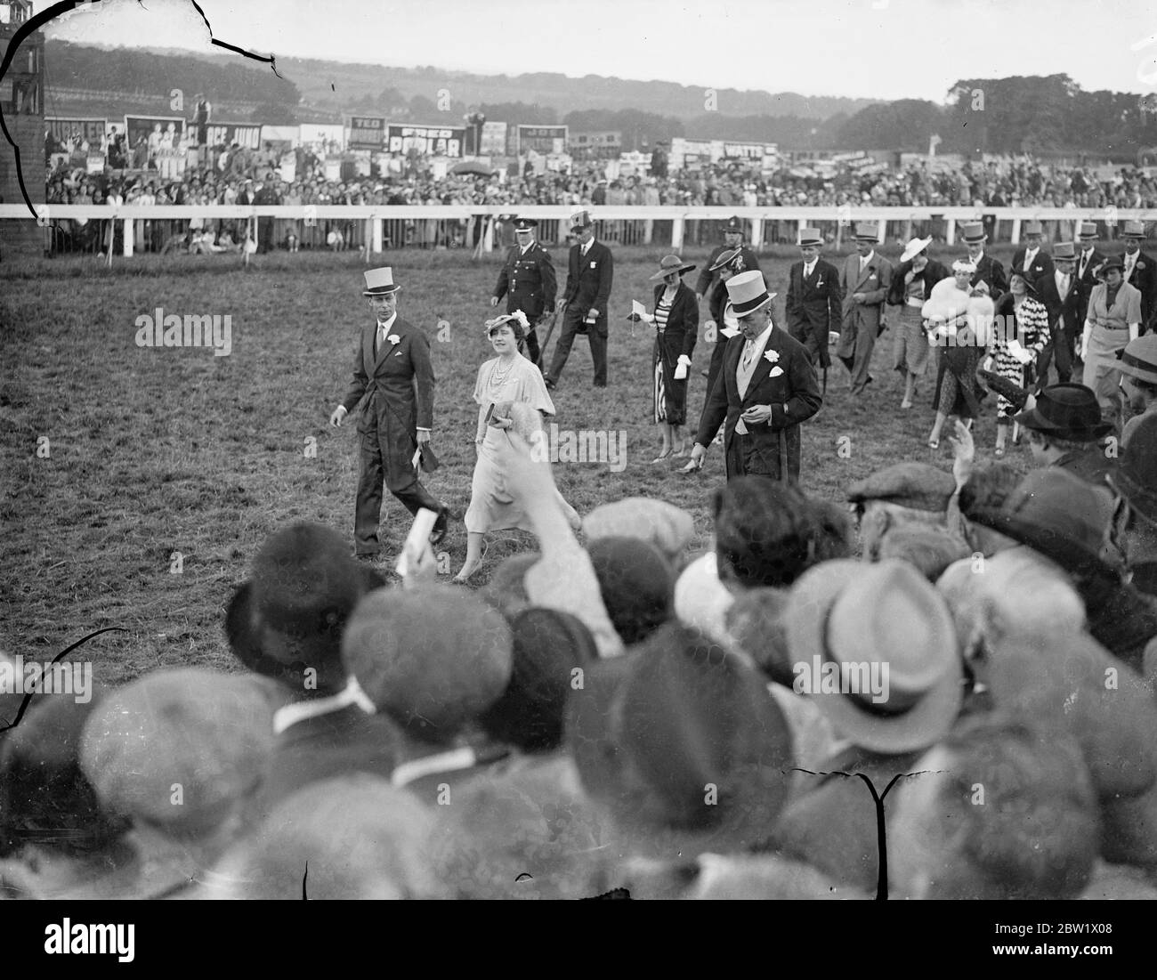 König und Königin gingen zum Fahrerlager in Epsom am Oaks Day. Der König und die Königin, die in drei Tagen einen zweiten Besuch abstatten, können sie den Kurs in Epsom hinunter zum Fahrerlager vor dem Beginn der Eichen gehen. Foto zeigt, der König und die Königin zu Fuß zum Fahrerlager in Epsom. Juni 1937 Stockfoto