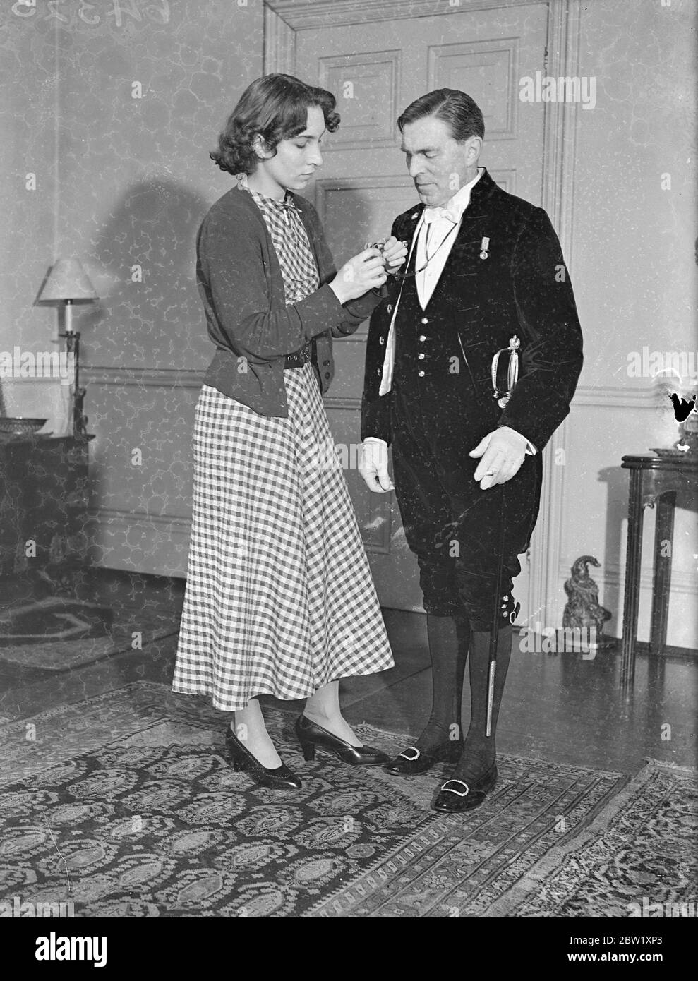 Künstler in Hofkleidung wird Krönungszeremonie in der Abtei malen. Der Künstler L. Campbell Taylor wird in Hofkleidung an der Krönungszeremonie in der Abtei teilnehmen und die Szene malen. Er hat alle Proben besucht und wird bei dieser eigentlichen Zeremonie Skizzen und Notizen machen, aus denen er später ein Bild aufbauen wird. Foto zeigt: Herr L. Campbell Taylor in Hofkleidung, mit seiner Frau in seinem Londoner Studio. Mai 1937 Stockfoto