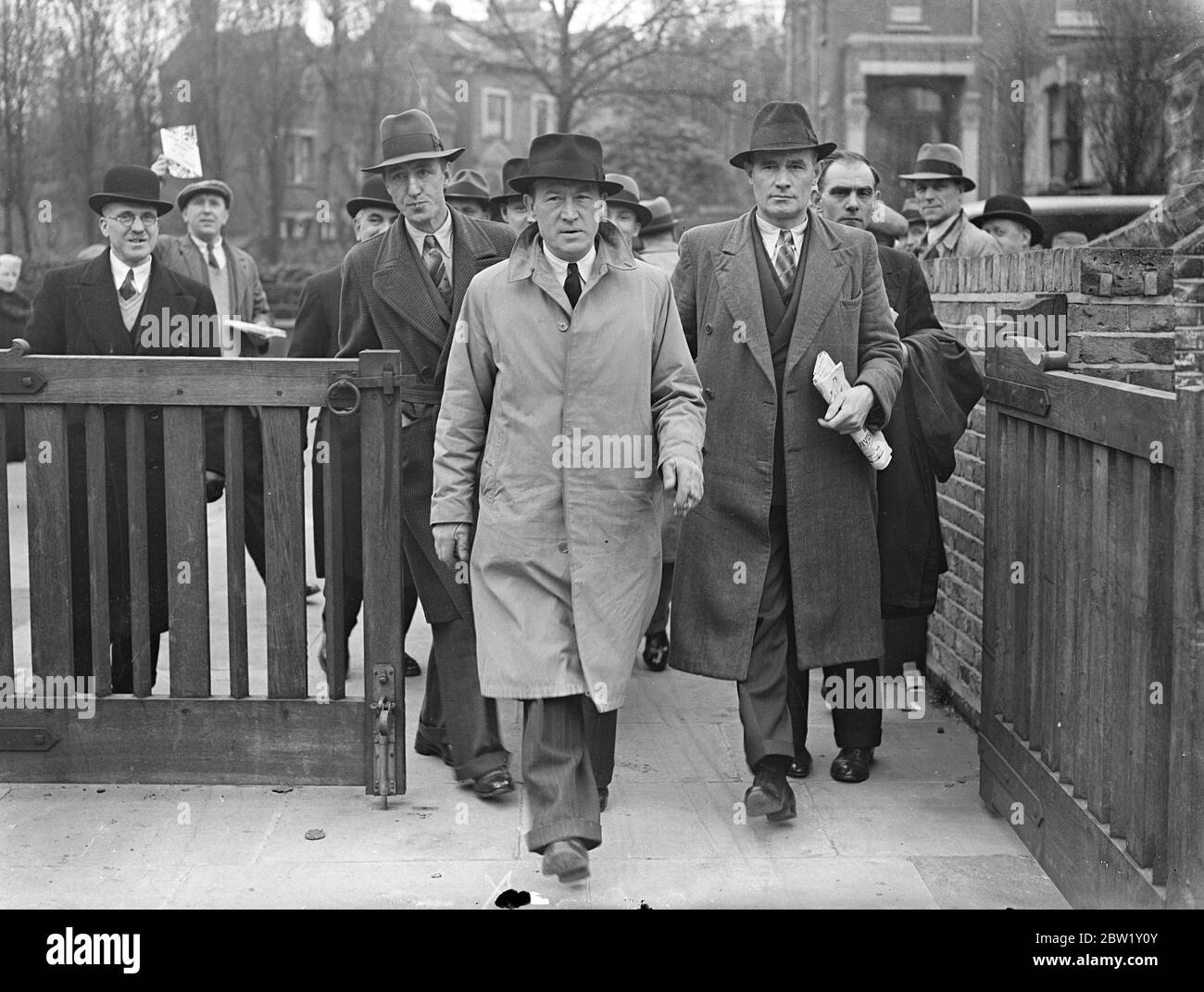 Busmen treffen sich in London, um Streikmaßnahmen zu unterstützen. Eine Versammlung von Busdelegierten der Transport and gen Workers Union fand in der Woodbury Hall Green Lanes, Stoke Newington, statt, als erwartet wurde, dass die endgültige Zustimmung zu den Streikmaßnahmen nach dem vollständigen Scheitern der Verhandlungen gegeben werden würde, die die ganze Woche über geführt wurden. Foto zeigt, Herr F Snelling, Vorsitzender des Zentralbuskomitees (Mitte, leichter Regenmantel) Ankunft mit heikel für das Treffen. 30. April 1937 Stockfoto