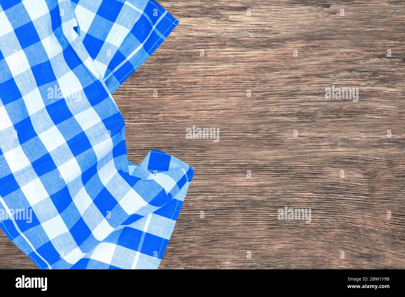 Topview aus blau kariertem Küchentuch, Textil, Tischdecke oder Serviette auf einem leeren rustikalen Holztisch. Vorlage für die Montage von Lebensmitteln und Produktdisplay. Stockfoto