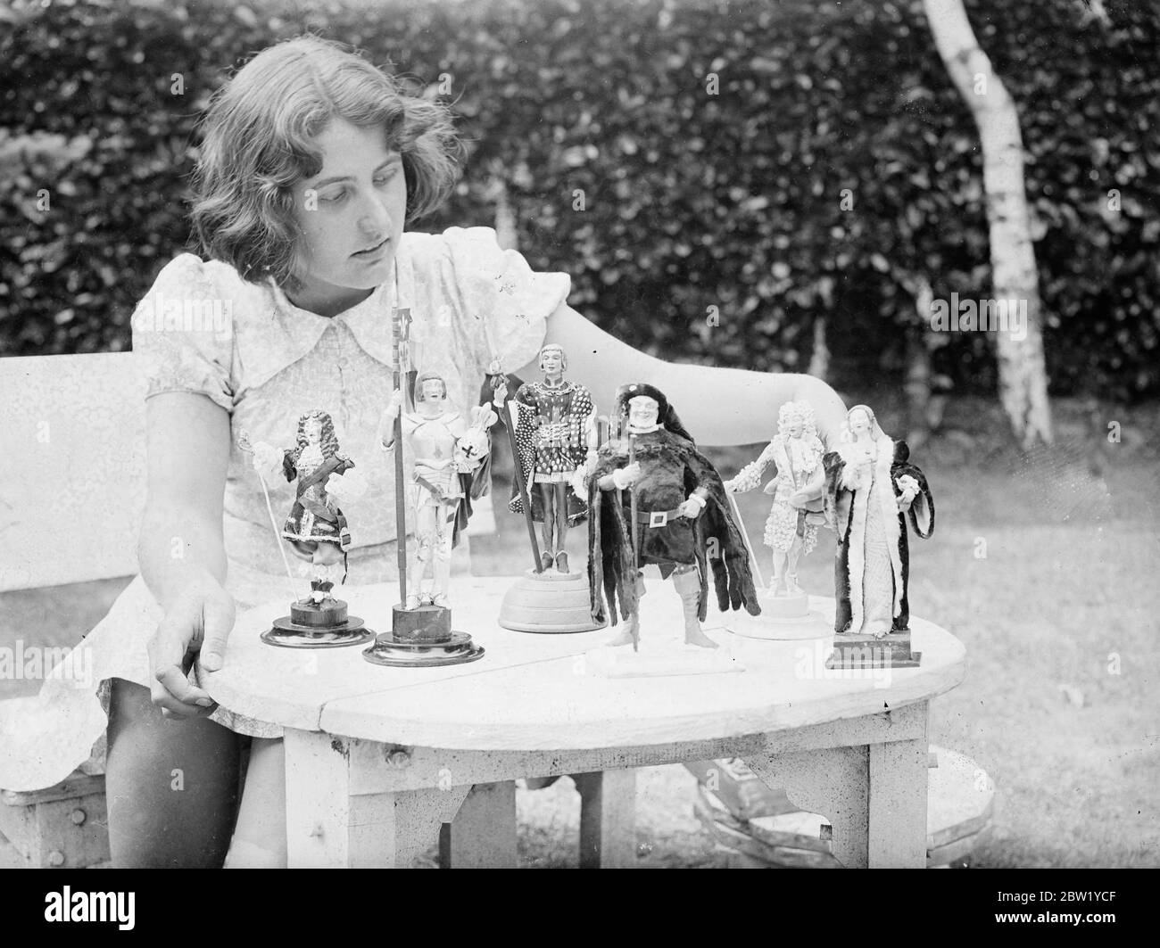 15-jähriges Mädchen macht ihren eigenen 'Festzug der Zeitalter'. Modelle berühmte historische Figuren. Obwohl sie erst 15 Jahre alt ist, ist Mary Nicoll von Byfleet ein schlaues Modell berühmter Persönlichkeiten der Vergangenheit. Alle Modelle, die etwa 7 Zoll hoch sind, sind akkurat Kostüme in Seide und Stickereien. Die Figur ist einem Drahtmodell nachempfunden und das Gesicht wird aus Marys Erinnerung kopiert. Mary hat ihren 'Festzug der Zeitalter' in ihrer Freizeit gemacht. Fotoausstellungen, Mary Nicoll war einige ihrer historischen Figuren, darunter Jeanne d'Arc, Henry VIII und Amber Lynn in ihrem Hause in Byfleet. 15. Juni 1937 Stockfoto