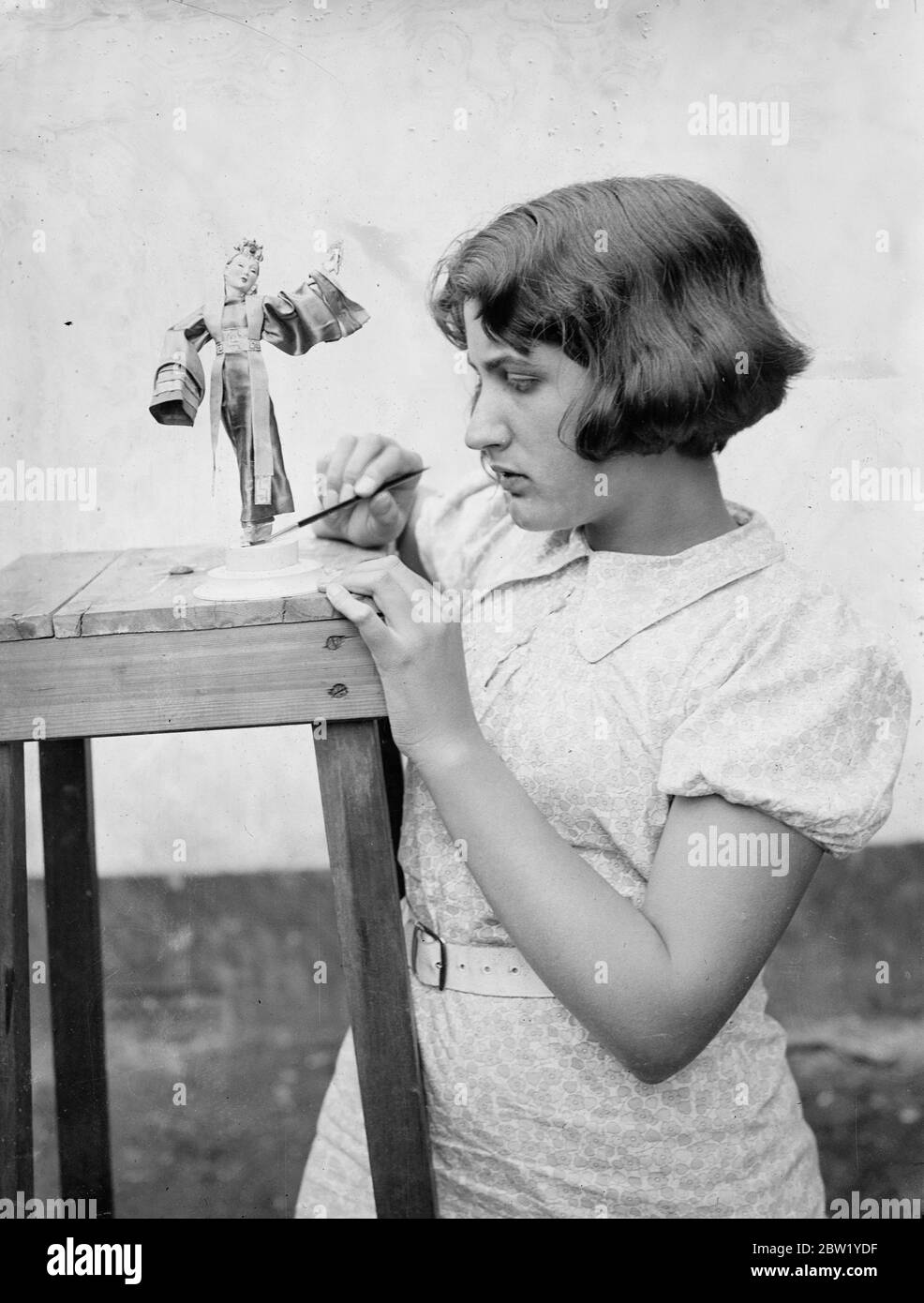 15-jähriges Mädchen macht ihren eigenen 'Festzug der Zeitalter'. Modelle berühmte historische Figuren. Obwohl sie erst 15 Jahre alt ist, ist Mary Nicoll von Byfleet ein schlaues Modell berühmter Persönlichkeiten der Vergangenheit. Alle Modelle, die etwa 7 Zoll hoch sind, sind akkurat Kostüme in Seide und Stickereien. Die Figur ist einem Drahtmodell nachempfunden und das Gesicht wird aus Marys Erinnerung kopiert. Mary hat ihren 'Festzug der Zeitalter' in ihrer Freizeit gemacht. Foto zeigt Mary Nicoll, die in ihrem Hause in Byfleet ein Modell einer koreanischen Tänzerin ausarbeitet. 15. Juni 1937 Stockfoto