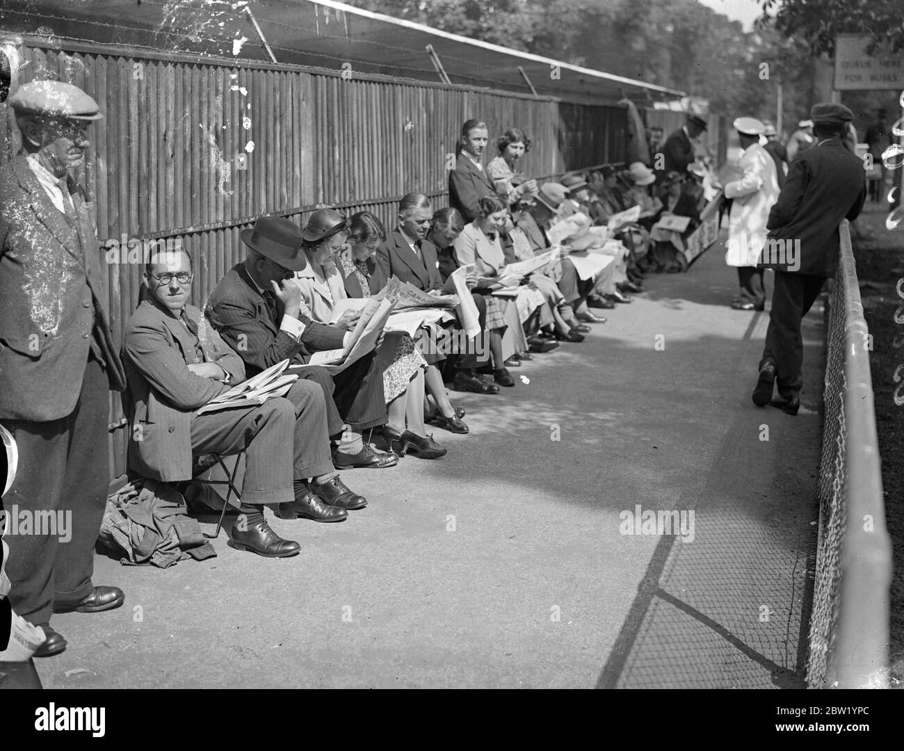 In Wimbledon stehen viele Schlangen für den ersten Frauentag an. Eine lange Schlange von Tennisbegeisterten wartete in Wimbledon auf den Eintritt zum zweiten Tag der Meisterschaft, wenn Frauen in Aktion sein würden. Fotoschauen, die große Menge wartet auf den Eintritt in Wimbledon. 22 Juni 1937 Stockfoto