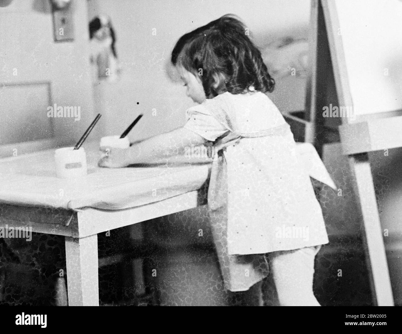 Marie begierig, die Arbeit an einem Meisterwerk in der Dionne Kindergarten in Kalender, Ontario beginnen. Die Dionee-Quintlets beginnen, den kreativen Drang zu erfahren, die mit Schmerz versorgten glücklichen Quins sind Bausteine und andere Mittel der Selbstdarstellung. 18 Juli 1937. Stockfoto