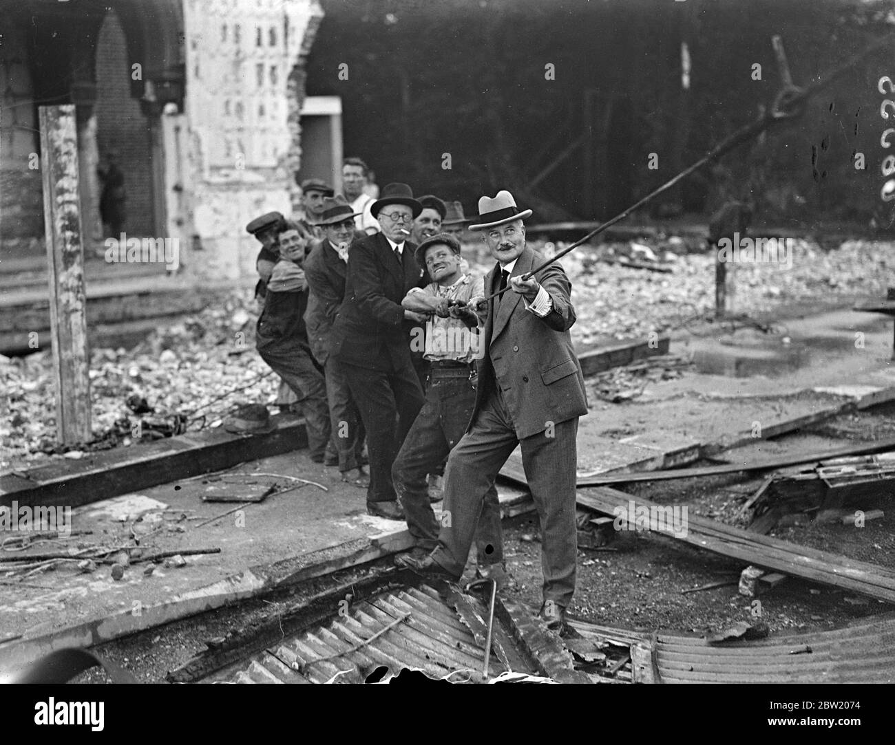 Sir Henry Buckland hilft, das große Skelett des nördlichen Querschiffs, auf der letzten Stufe der Zerstörung des Kristallpalastes, abzureißen. Sir Henry Buckland, der Generaldirektor des Palastes, zog die feuerroten Ruinen nieder. 15 Juli 1937. Stockfoto