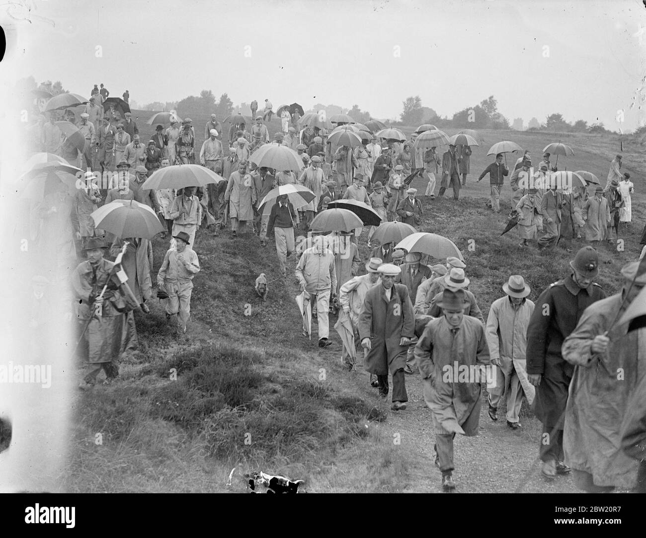 Die Menschenmenge, die Schirme auf dem durchnässten Golfplatz in Walton Heath trägt, wo sie Henry Cotton (Großbritannien) und Densmore Shute (USA) beim Spielen um die Weltmeisterschaft beobachten. 12 Juli 1937 Stockfoto