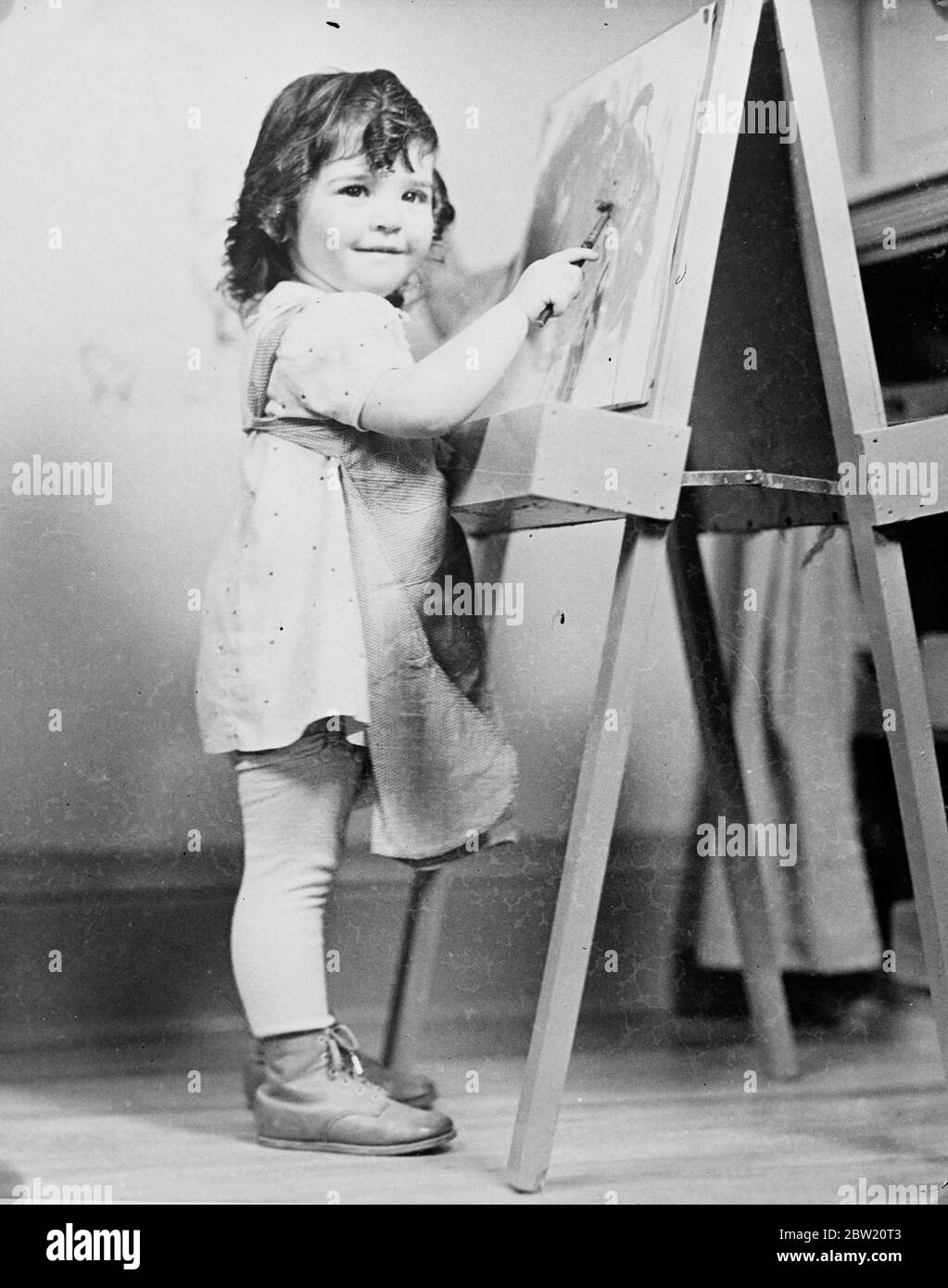Yvonne lächelt stolz, als sie ihre Bürste auf die Staffelei in der Dionne-Kinderstube in Calendar, Ontario, anwendet. Die Dionee-Quintlets beginnen, den kreativen Drang zu erfahren, die mit Schmerz versorgten glücklichen Quins sind Bausteine und andere Mittel der Selbstdarstellung. 18 Juli 1937. Stockfoto