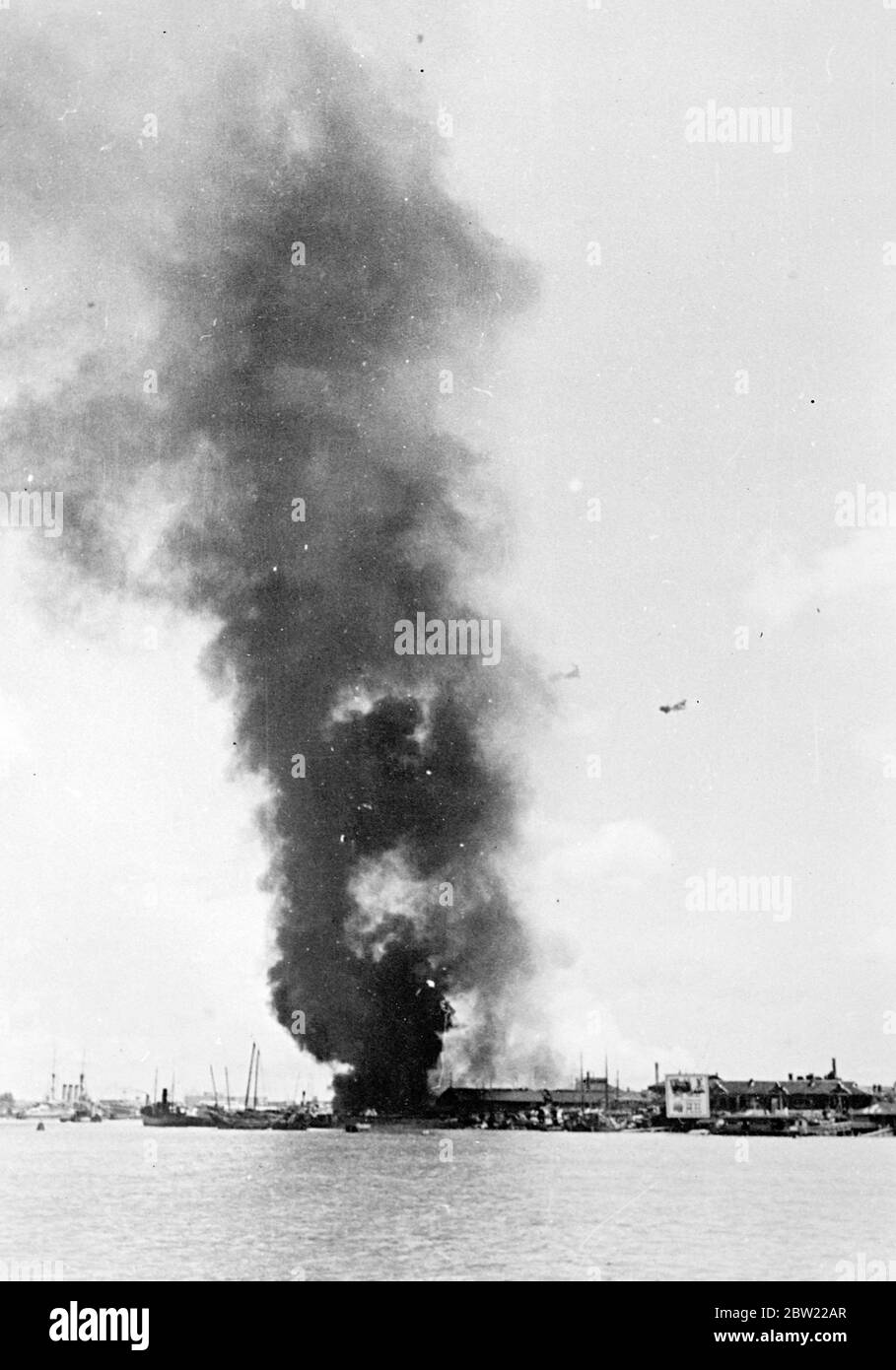 Japanische Marinewaffen verursachen riesige Brände in Pootung, Shanghai. Sirius-Feuer wurden am Pooting Point, am Ufer des Whangpoo Flusses gegenüber Shanghai gestartet, durch Schüsse von japanischen Kriegsschiffen, die versuchten, chinesische Batterien zum Schweigen zu bringen. Trotz der Überanstrendung durch die Japaner zeigen jüngste Berichte jedoch, dass es den Chinesen gelungen ist, neue Batterien aufzubringen, und dass Prinz Hiroyoshi Fushimi, Mitglied der kaiserlichen japanischen Familie und Kommandeur der japanischen dritten Zerstörer-Flottille, während eines Artillerieduells in seinem Schiff verletzt wurde. Foto zeigt, eine Spalte dichten Rauch steigt aus hu Stockfoto