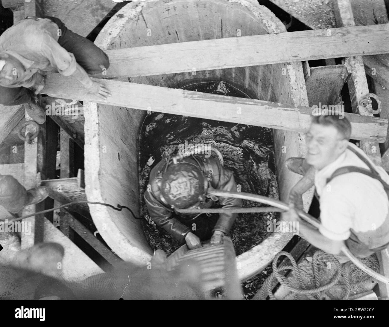 Tauchen Sie während der Umbauarbeiten am Londoner Dock der Royal Victoria in das inky-Wasser eines Caisson. Die Arbeiten kosten Â£1,500,000 alte Steinstege werden abgerissen, um Platz für 5000 Fuß neue Tiefseestäben zu machen. Nach Abschluss der Regelung wird London die modernsten Docks der Welt. 17. September 1937. Stockfoto