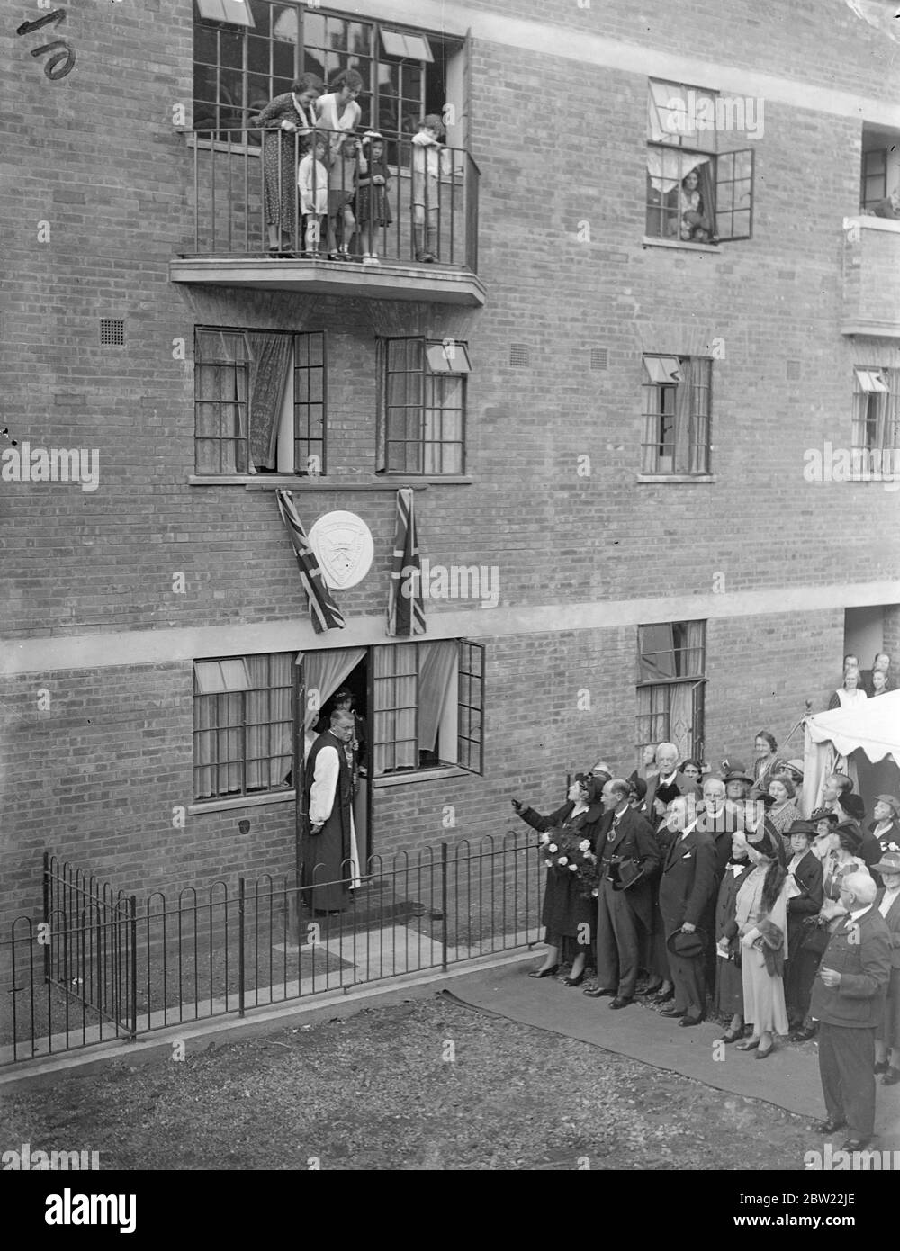 Premier's Frau eröffnet neue Wohnungen in Kensington. Frau Neville Chamberlain, Ehefrau des Premier, eröffnete 24 neue Wohnungen, die wie Häuser mit Balkonen in Basing Road, North kensington, london gebaut wurden. Jede Wohnung hat einen separaten Eingang, Wohnzimmer, Kochnische, Bad und mehrere Schlafzimmer. Sie wurden von der Church Army und dem Kensington Council als Ersatz für Slums gebaut. Foto zeigt, Frau Neville Chamberlain enthüllt die Tablette vor den neuen Wohnungen. 28. September 1937. Stockfoto