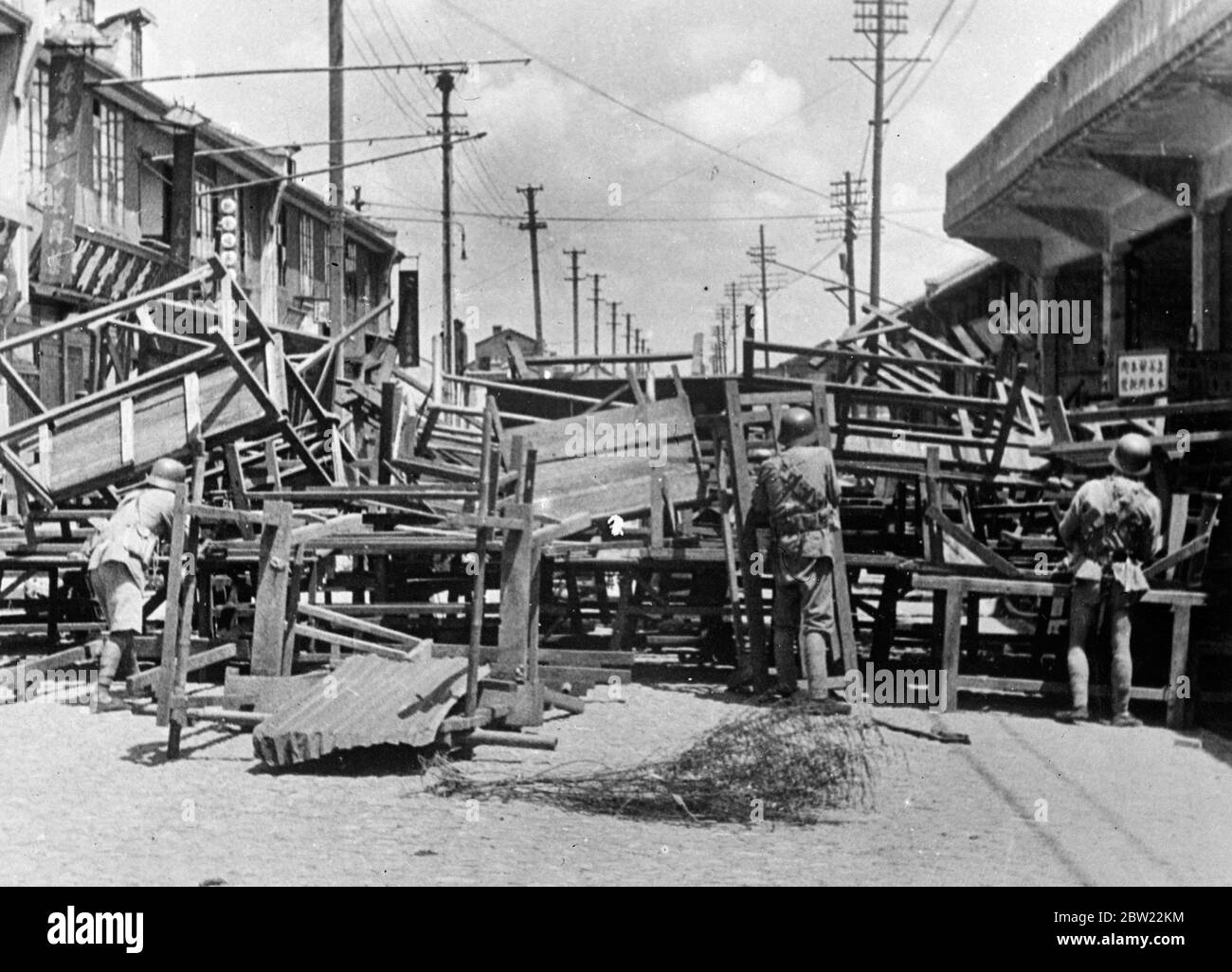 Chinesische Soldaten hinter der Straßenbarrikade, von der sie eine japanische Marine Landepartei, Shanghai gekämpft. Die Barrikade wurde schnell zusammen mit Möbeln und Holzarbeiten aus Gebäuden geworfen. Das chinesische Viertel von Shanghai wurde durch die fortwährenden Luftangriffe und Artilleriebeschuss der japanischen Streitkräfte völlig zerstört. Unzählige Menschen haben ihr Leben verloren und viele mehr haben ihr Zuhause und ihre Habseligkeiten verloren. Trotz der Wildheit der Japaner kämpfen die Chinesen immer noch stark zurück und halten weiterhin am japanischen Vormarsch fest. 13. September 1937. Stockfoto