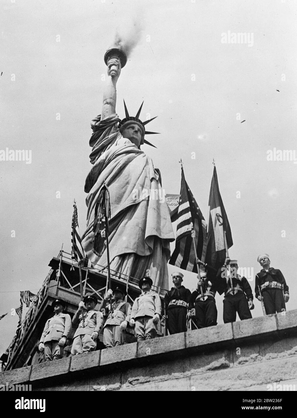 Die Fackel der Freiheit brennt, als die Amerikaner an den 150. Jahrestag der Verfassung erinnern. Der hundertfünfhundertfünfhundertste Jahrestag der Unterzeichnung der Verfassung der Vereinigten Staaten von Amerika wurde auf Liberty Island, am Fuße der Freiheitsstatue im New Yorker Hafen, gefeiert. Die Feierlichkeiten dauerten eine Woche. Foto zeigt, eine Ehrenwache der amerikanischen Armee, Marine und Luftwaffe stehen zur Aufmerksamkeit als Rauch aus der Fackel der Freiheitsstatue gegossen, die die Eröffnung der Feierlichkeiten signalisieren. 20. September 1937 Stockfoto