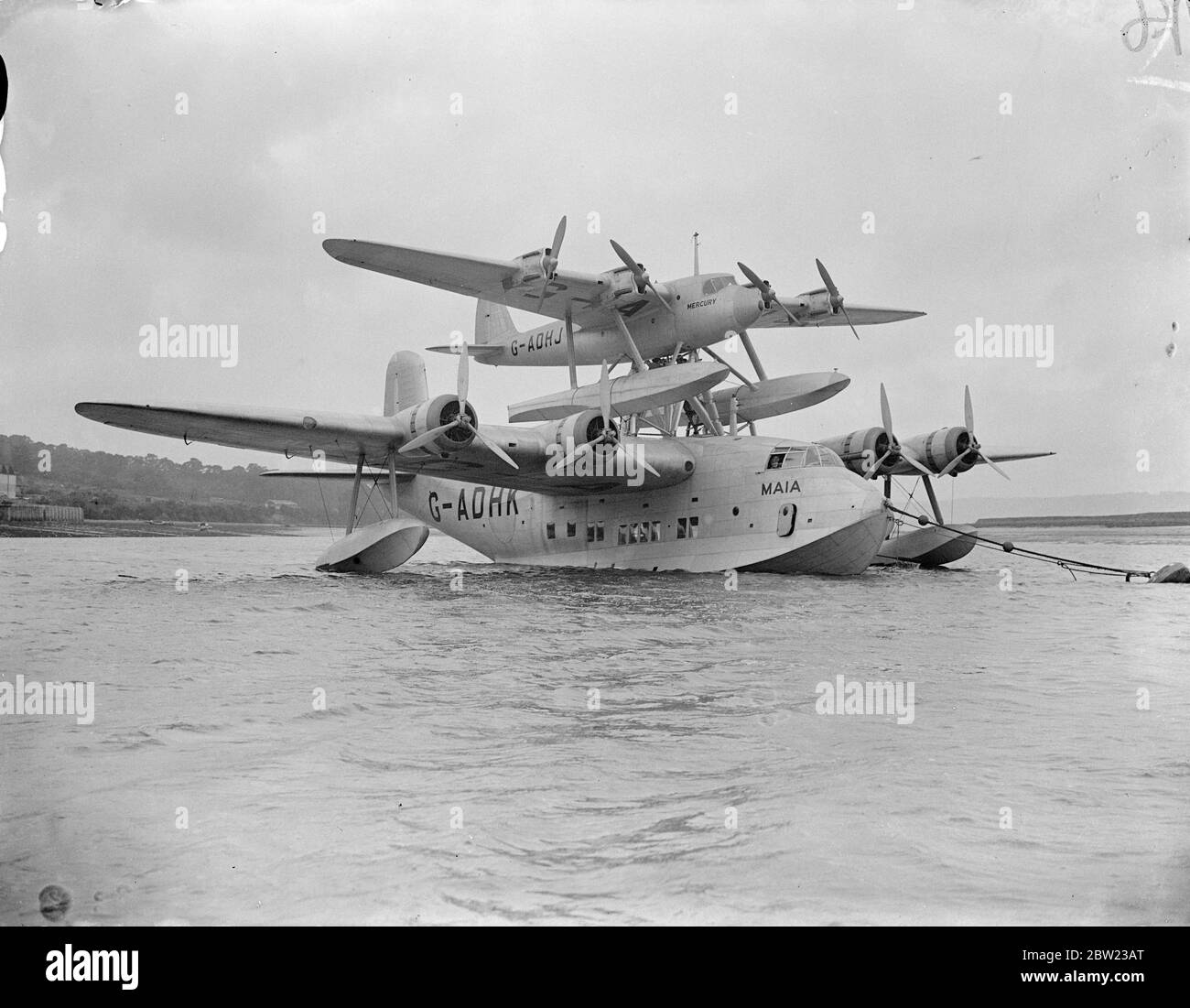Die beiden Teile der Mayo besuchen Flugzeug die Pick ein Rückflugzeug und jetzt in Rochester abgeschlossen, wo das Quecksilber für Verletzte die Forderung wurde auf der Maia 3350 ps-Flying Boat platziert. Das Flugzeug wird voraussichtlich Indien und New York innerhalb von Tagen Non-Stop-Flug bringen. Die beiden Flugzeuge als Arbeiter vollendeten die Befestigung der kleineren Ebenen an das fliegende Boot in Rochester. 12. Oktober 1937. Stockfoto