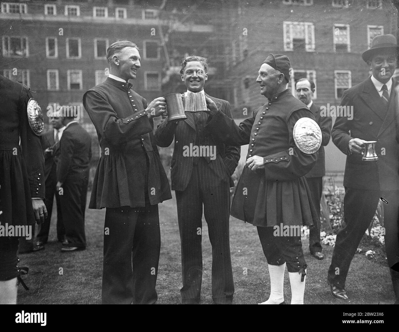 William Sylvester wird von seinem Bruder und seinem Vater getoastet, der bereits Gewinner des Doggett's Coat and Badge Race war, nachdem er beim 223. Jährlichen Sculling Race, das über eine 4 Meilen lange Strecke von London Bridge nach Chelsea Bridge stattfindet, gewonnen hat. Der Wettbewerb wurde 1715 von Thomas Doggett gestartet, der den Preis anbot, um den Beitritt für König George I zu gedenken.der Sieger des Rennens erhält einen roten Mantel mit einem silbernen Abzeichen auf dem linken Arm. 23 Juli 1937. Stockfoto