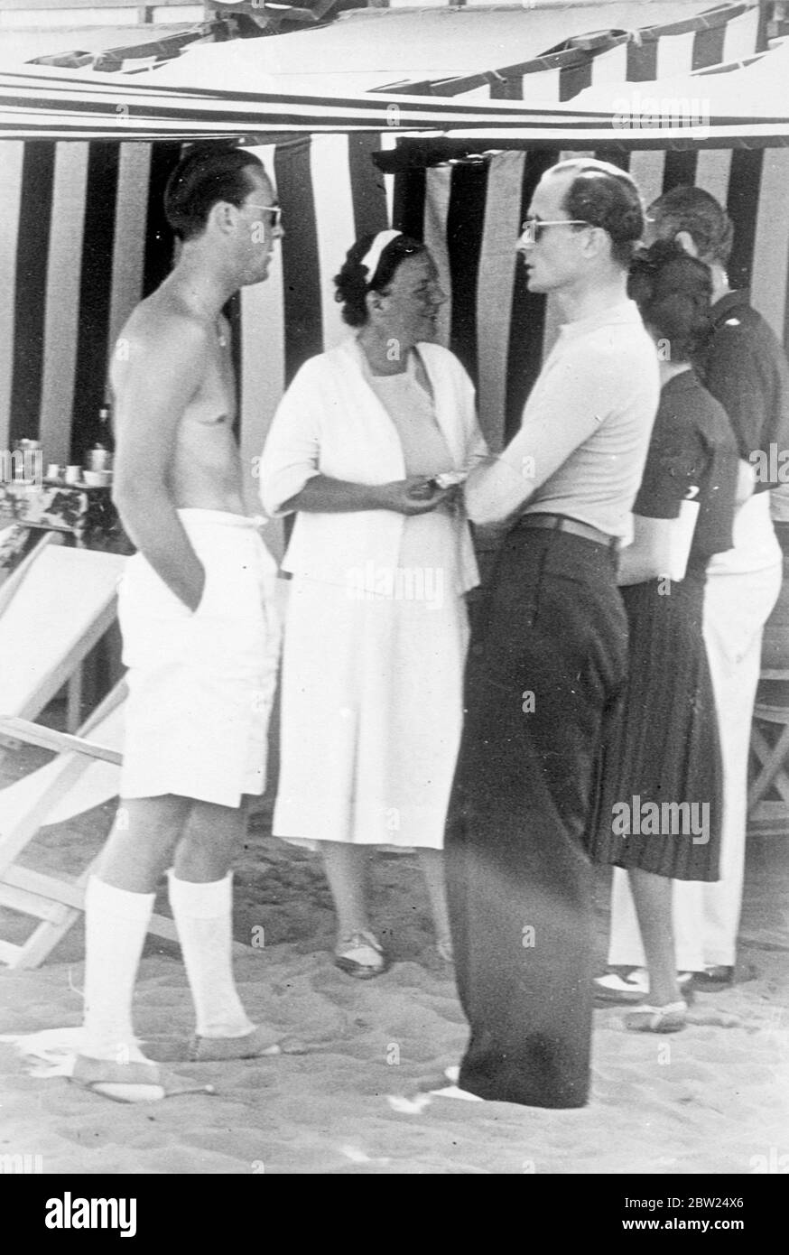 Graf Haugwitz Revention spricht mit Prinzessin Juliana und Prinz Bernhard am Lido. Graf Haugwitz Reventlow unterhielt sich mit Prinzessin Juliana und Prinz Bernhard der Niederlande, als sie sich am Strand am Lido in Venedig trafen. Der Graf traf auch seine entfremdete Frau, die ehemalige Barbara Hutton, und erklärte danach, dass alle Hoffnung auf eine Versöhnung aufgegeben worden sei. Fotoausstellungen, Graf Haugwitz Reventlow (rechts) im Gespräch mit Prinz Bernard in Shorts und Prinzessin Juliana am Strand am Lido. Bis 21. August 1938 Stockfoto