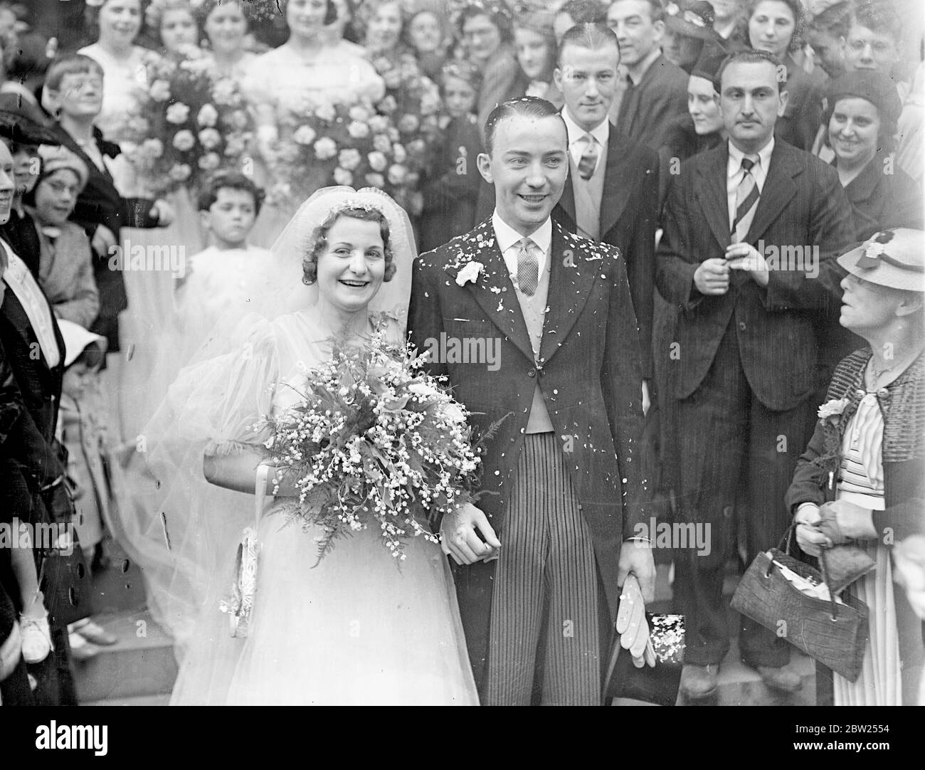 Besitzer des Hundderby Gewinner ist verheiratet in Brompton Oratory. Jack Walsh, der Besitzer von Lane keel, Gewinner des Greyhound Derby, war in Brompton Oratory mit Miss Ivy Sanders verheiratet. Alsh hat seiner Braut, Madelast April, versprochen, dass er ihr den Greyhound Derby Cup als Hochzeitsgeschenk überreichen würde. Foto zeigt, die Braut und Bräutigam verlassen durch die große Menge nach ihrer Hochzeit heute (Sonntag). Juli 1938 Stockfoto