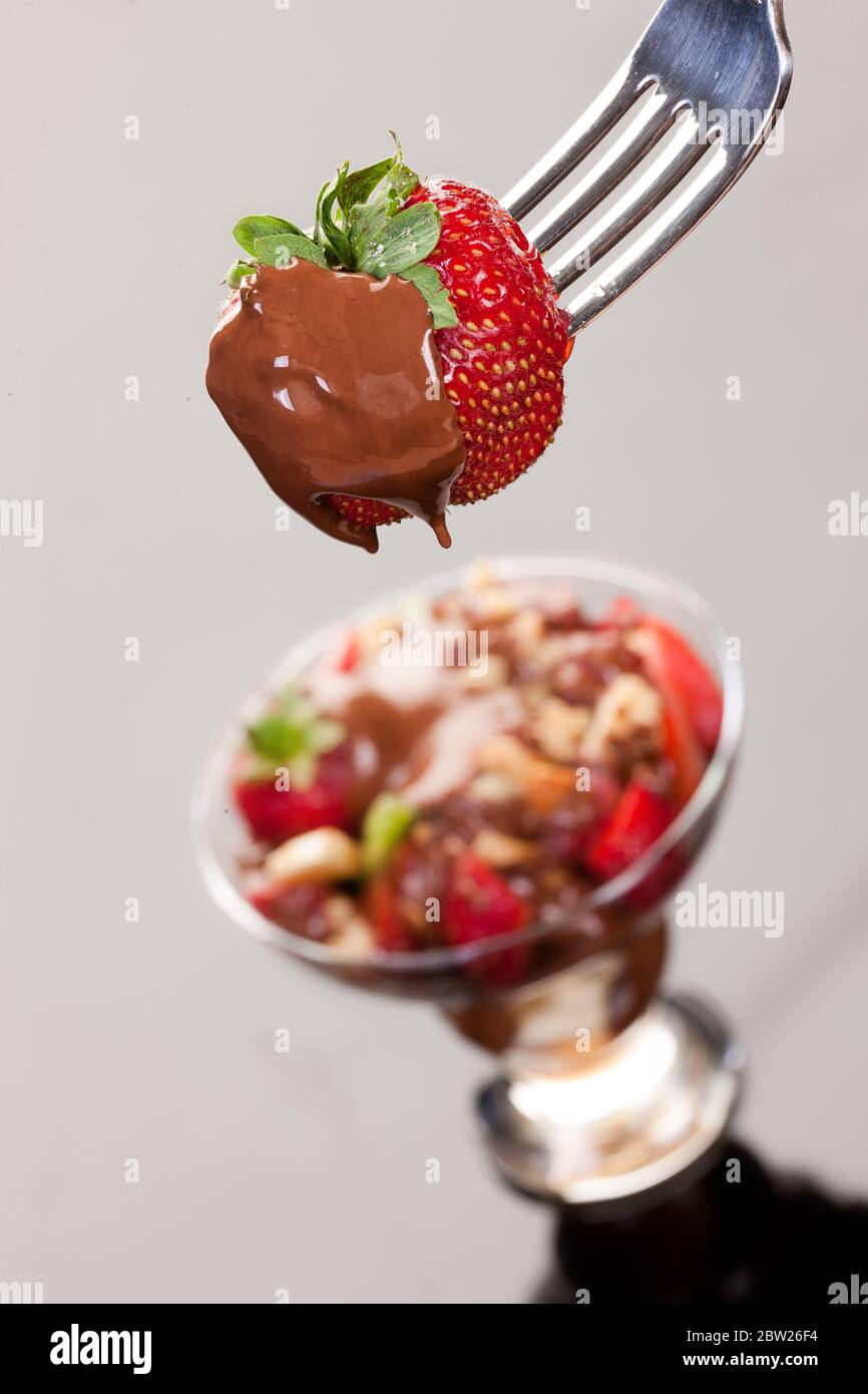 Erdbeere in Schokolade auf einer Gabel auf isoliertem Hintergrund Stockfoto