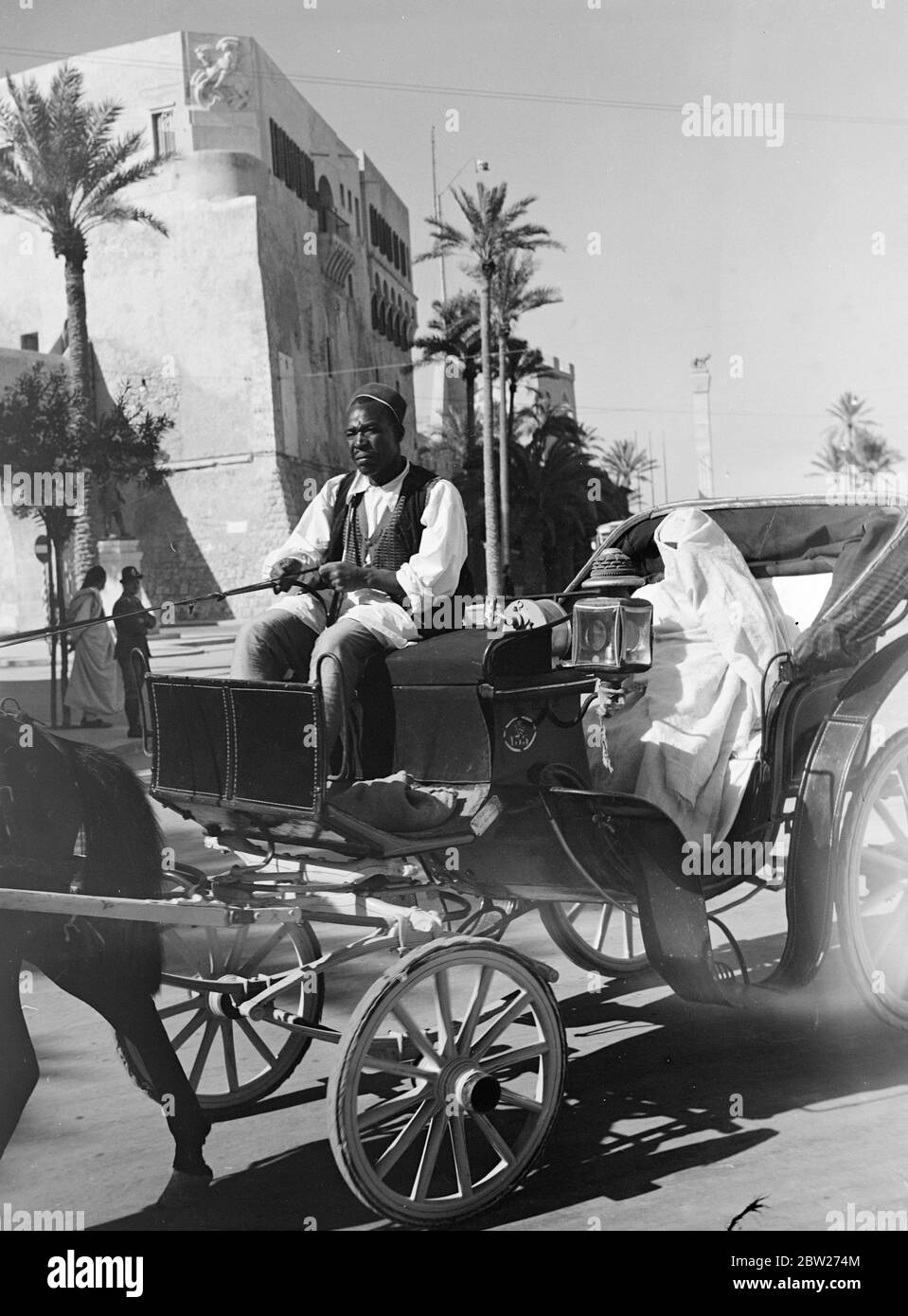 Libyscher Markt. Neugierige Besichtigungen und arabische Frau, die in einem arabischen Pferdehaus durch Tripolis gefahren wird. Die arabische Frau hält ihre Gesichter immer noch bedeckt und sieht mit einem Auge durch einen kleinen Raum in ihrer Decke wie Kleidung. Stockfoto