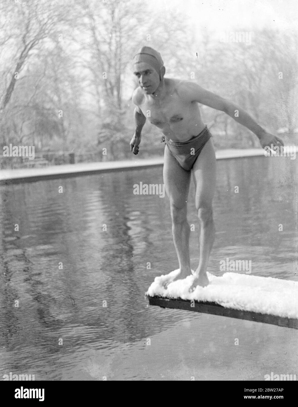 Schwimmen im Winter. Ein Mann, der in das kalte Wasser tauchend. Er steht auf einem schneebedeckten Brett. 1933 Stockfoto