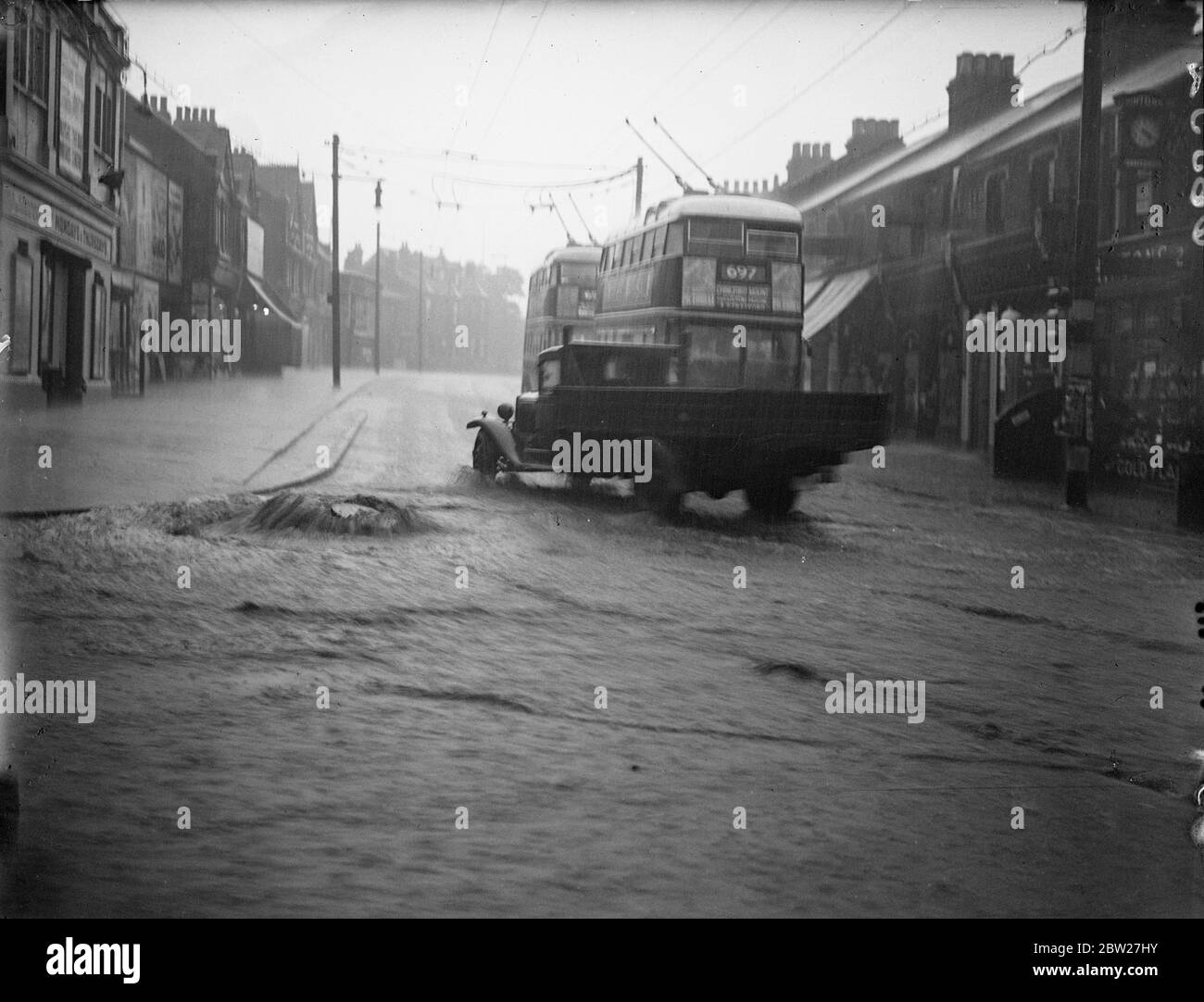 Ein Schachtloch, das in der überfluteten Kreuzung von Chingford Road und Forest Road Walthamstow aufgezwungen wurde, sintflutartige Regenfälle und überflutete Straßen und Häuser, folgte einem schrecklichen Sommergewitter, das in Walthamstow Chaos verursachte. 15 Juli 1937. Stockfoto