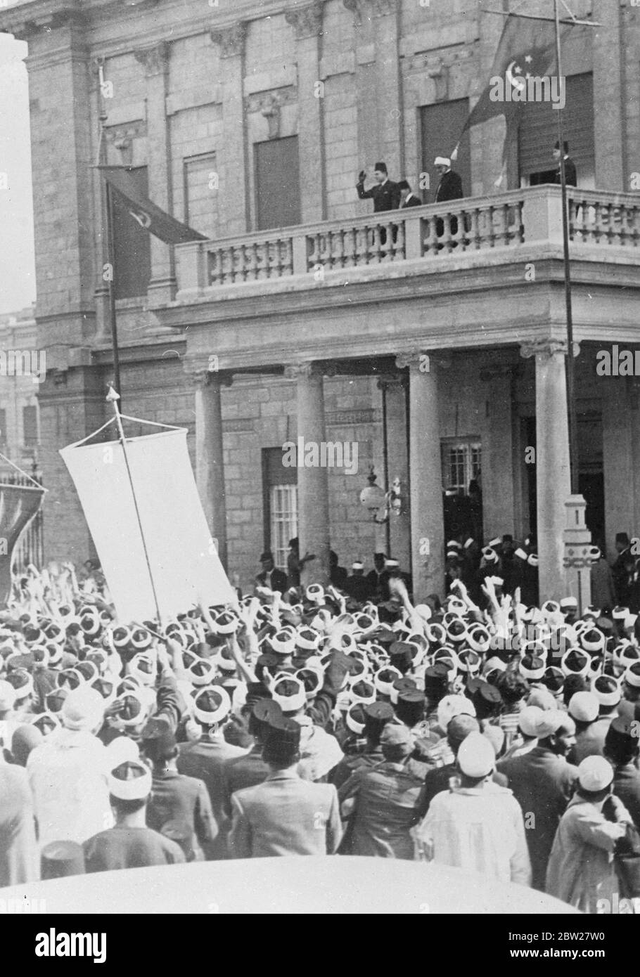 Die Hochzeit von König Farouk in Kairo. Mit traditioneller muslimischer Zeremonie wurde der 17-jährige König Farouk von Ägypten im Koubbeh-Palast in Kairo mit der Richterin des ägyptischen Berufungsgerichts, Frau Farida Zulficar Pasha, verheiratet. Foto zeigt, König Farouk winkt vom Balkon zum Abdin-Palast, Kairo, als Reaktion auf den Jubel der Beduinen, die aus der Wüste gekommen waren, um an den Hochzeitsfeiern teilzunehmen. 23. Januar 1938. Stockfoto