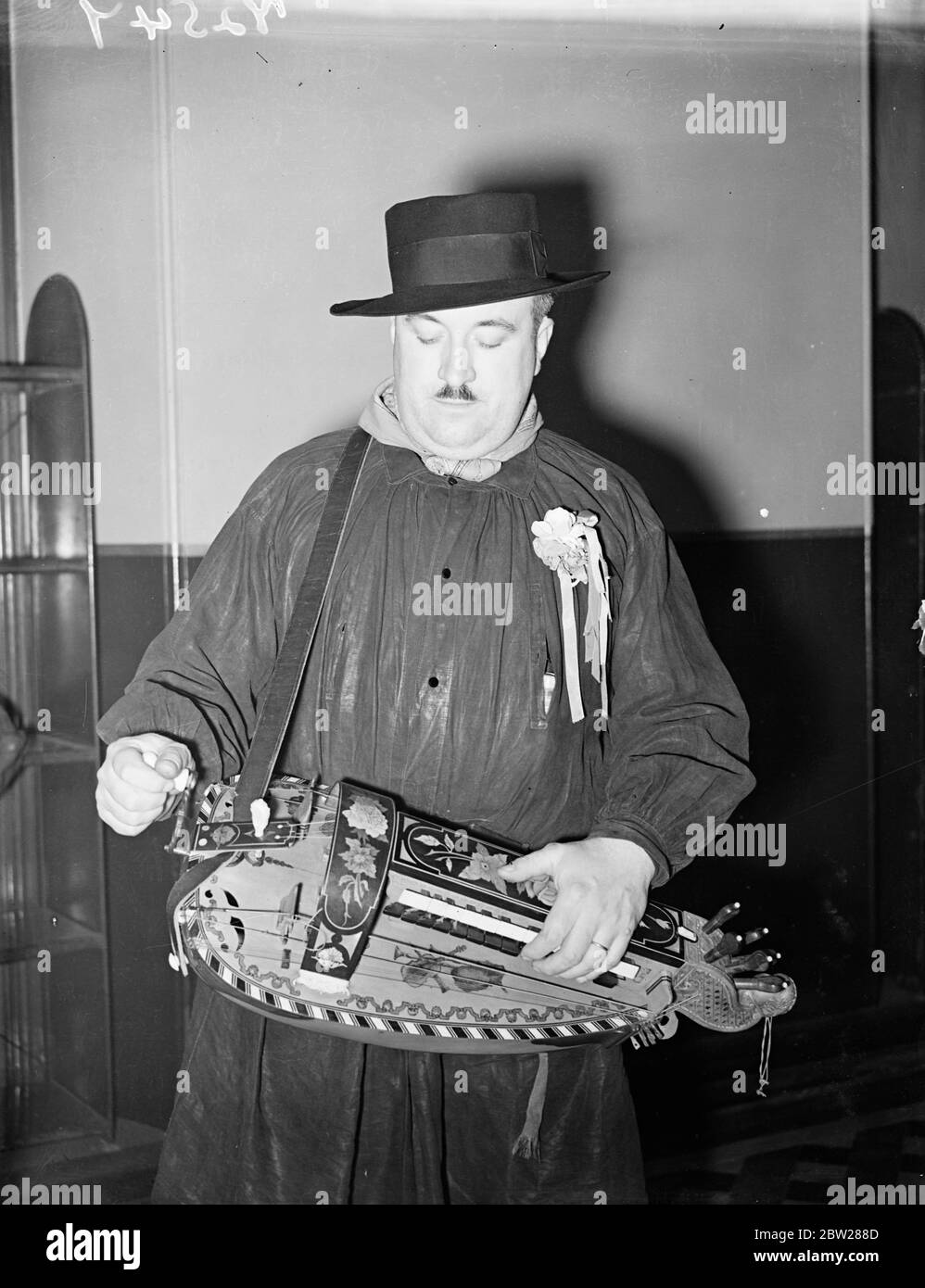 Französische Volkstänzer Proben in der Albert Hall für jährliche Festival. In bunten Kostümen, deren Stil über viele Jahrhunderte hinweg überliefert ist, sind die Teams Volkstänzer aus allen Teilen Großbritanniens und eine Gruppe aus Berry, Frankreich, die in der Royal Albert Hall, London, für das Folk Dance Festival, das morgen (Samstag) dort stattfindet, einstudiert haben. Foto zeigt, einer der Musiker des Berry (Frankreich)-Teams spielt die malerische Vielle , die die Musik für den Tanz bietet, bei der Probe. Januar 1938 Stockfoto