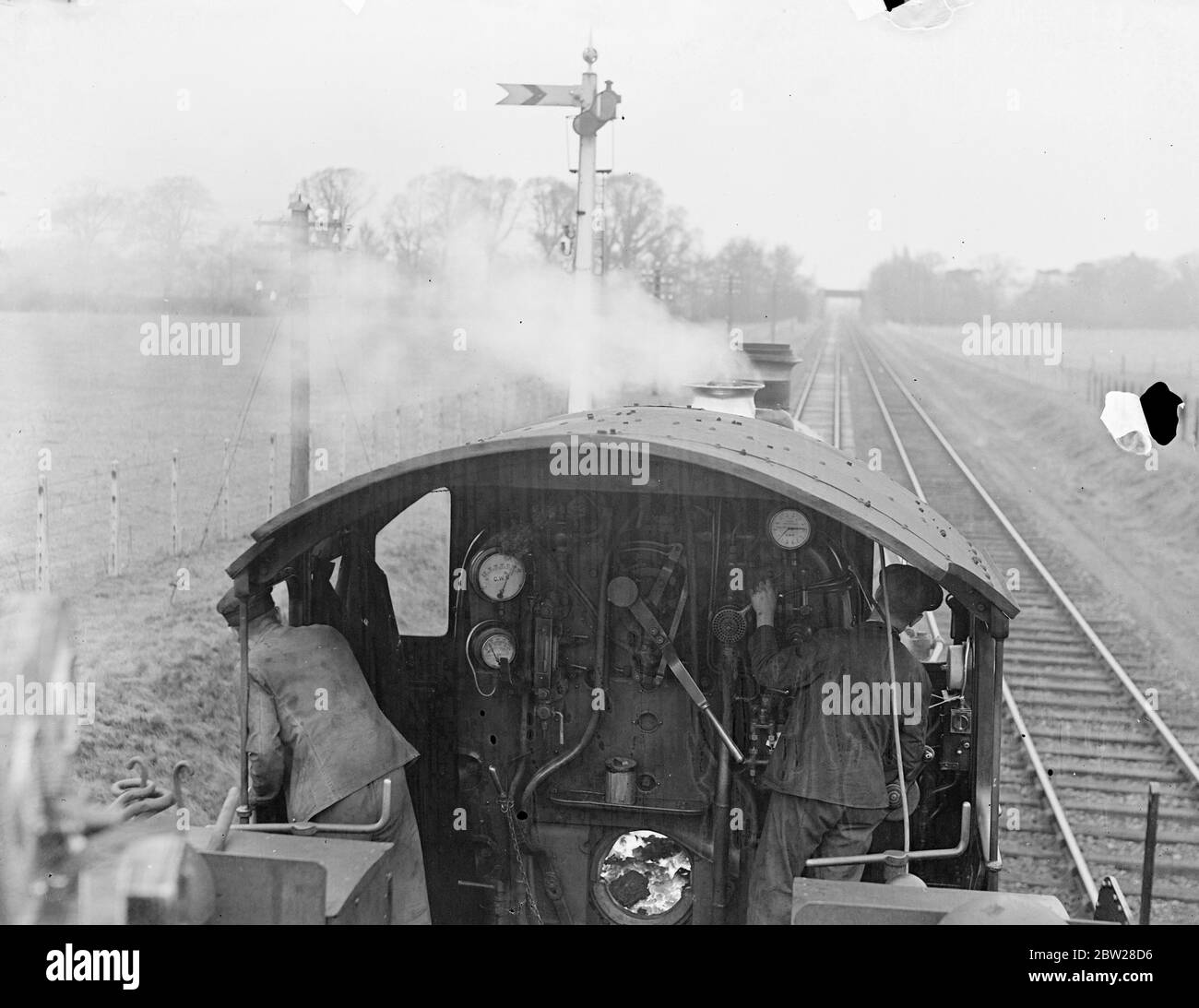 Die britischen Eisenbahnen überwinden die Nebeldrohung - hörbare Signale warnen den Fahrer und bremsen. Ein von Mitarbeitern des Eisenbahnpersonals erfundenes Gerät, das den Fahrern eine akustische Warnung gibt, wurde als Sicherheitshilfe auf dem Great Western Railway System in England installiert. Wenn die Linie frei ist, klingelt eine Glocke von der Fahrerseite, die ihm das Vorwegrecht gibt. Sollte das Signal auf 'Vorsicht' stehen, ertönt eine Sirene und die Bremsen werden automatisch im Zug betätigt. Und ich bin sicher, Sie unter der Lokomotive montiert verbindet mit der Rampe und gibt so das Signal an den Fahrer. Mit Hilfe dieses neuen sa Stockfoto