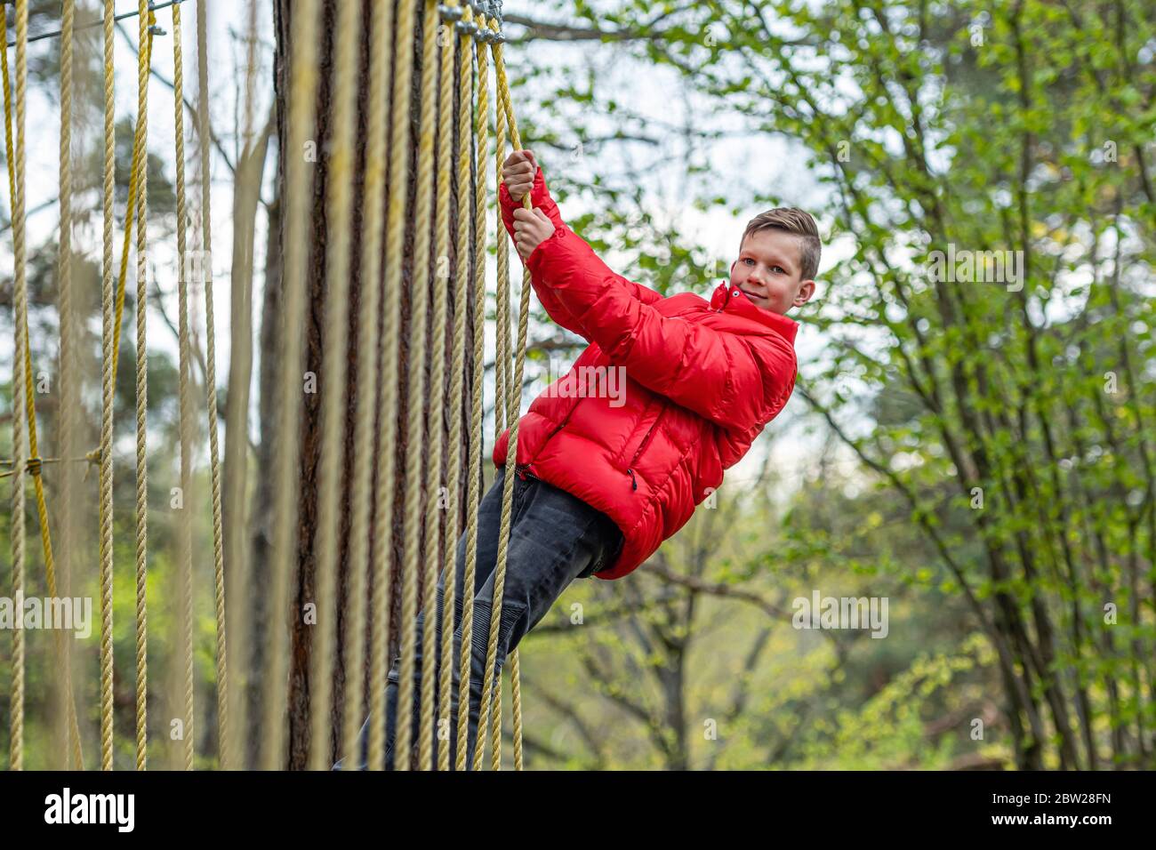 Gesunde Teenager Schuljunge genießen Aktivität in einem Kletterabenteuer Park an einem Frühlingstag Stockfoto