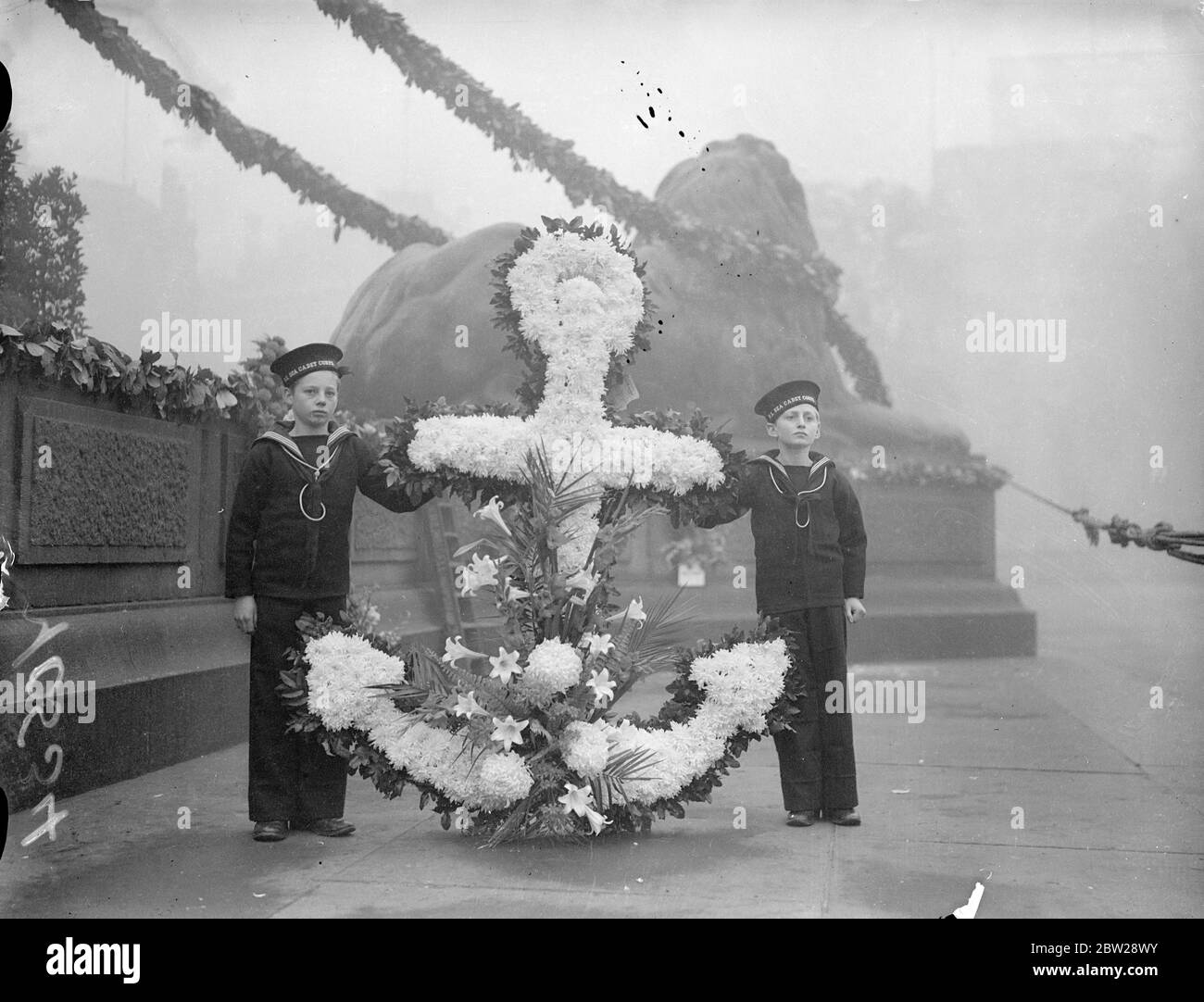 Geheimnisse des Lay Kranz auf Nelson Monument am Trafalgar Day.. Am Trafalgar-Tag wurden Kränze auf die Nelson-Säule am Trafalgar Square gelegt. Dies ist der 132. Jahrestag der Schlacht. Foto zeigt zwei junge Mitglieder des Sea Cadet Corps, mit einem Kranz von der Royal Naval Barracks, Portsmouth, an der Nelson-Säule. 21. Oktober 1937 Stockfoto