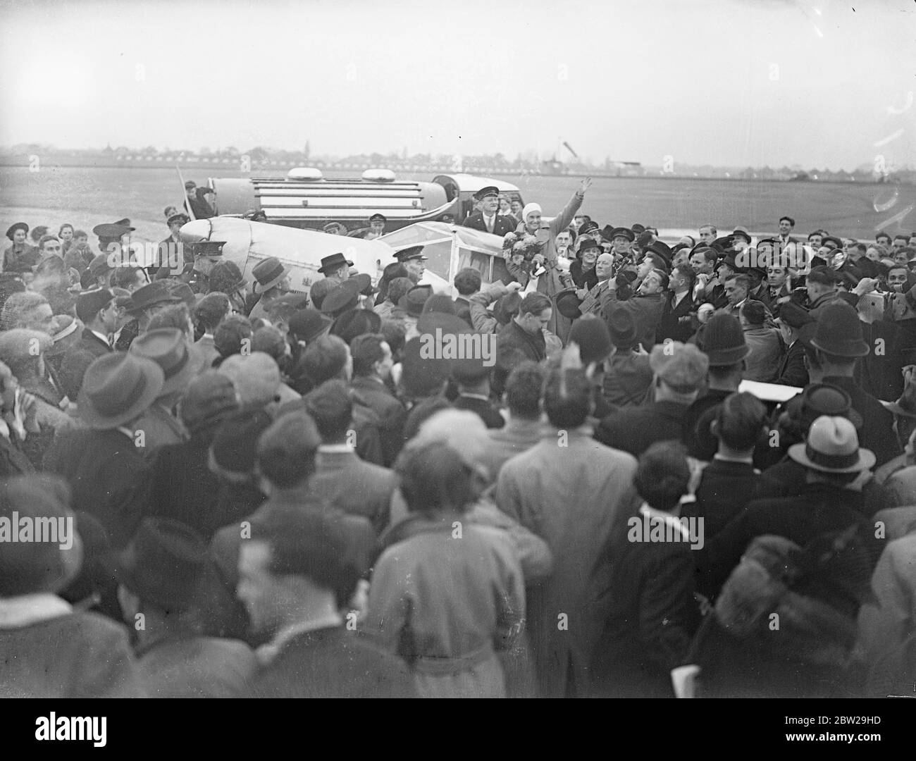 Jean Batten schlägt Australien nach England Rekord um 14 1/2 Stunden. Nachdem sie in ihrer letzten zermürbenden Runde gegen Erschöpfung und Stürme gekämpft hatte, wurde Jean Batten, das neuseeländische Luftmädchen, von jubelnden Menschenmengen begrüßt, als sie in Croydon landete, nachdem sie Jim Broadbents Rekord von Australien nach England um 14 1/2 Stunden gebrochen hatte. Sie war in Lympne gelandet, hatte in fünf Tagen 18 Stunden den ersten Alleinflug absolviert und kam nach Croydon. Foto zeigt Jean Batten im Cockpit eines Flugzeugs in Croydon, mit einem Blumenstrauß. 24. Oktober 1937 Stockfoto
